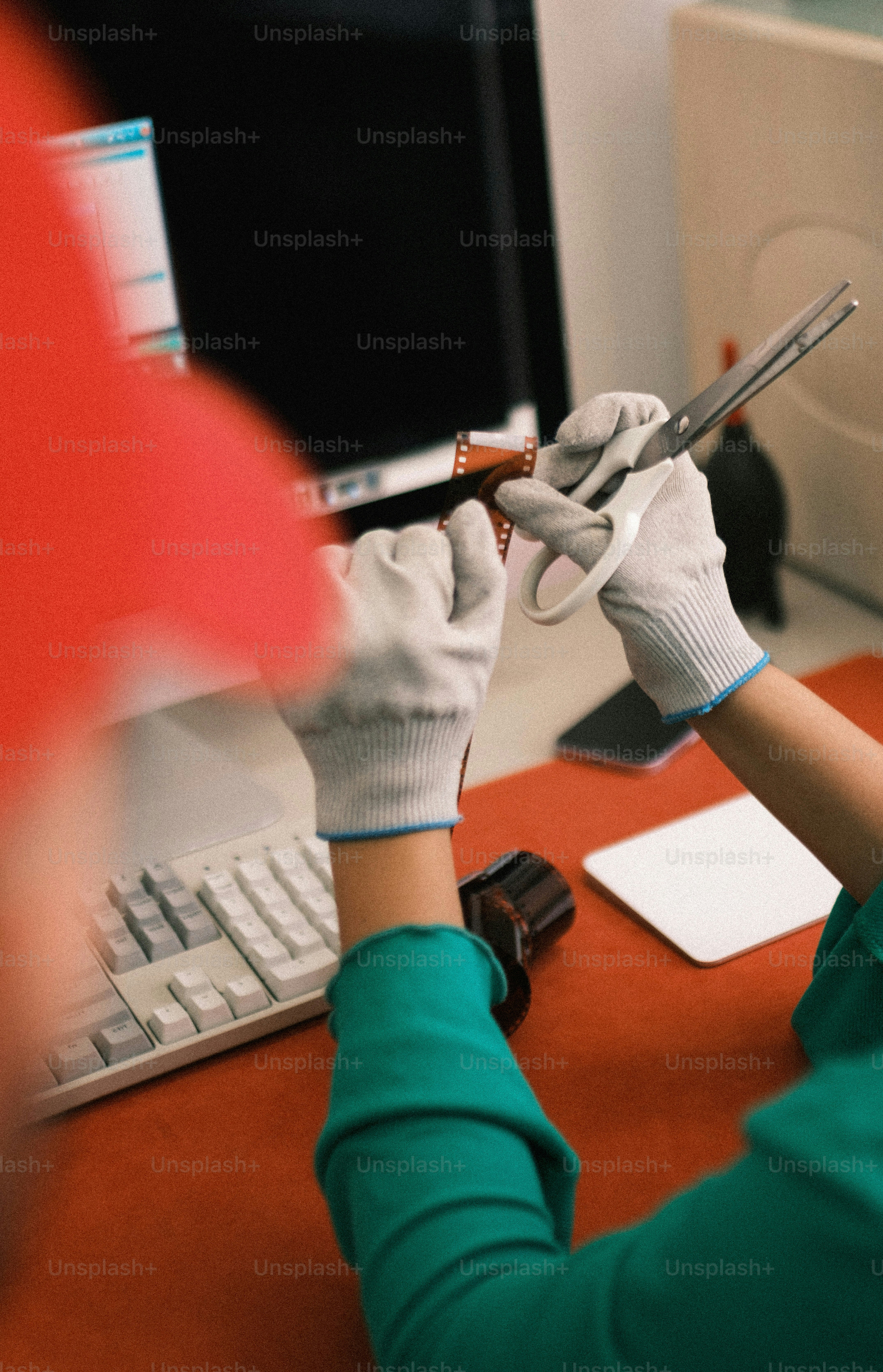 Mãos enluvadas cortando negativos de filme com tesoura