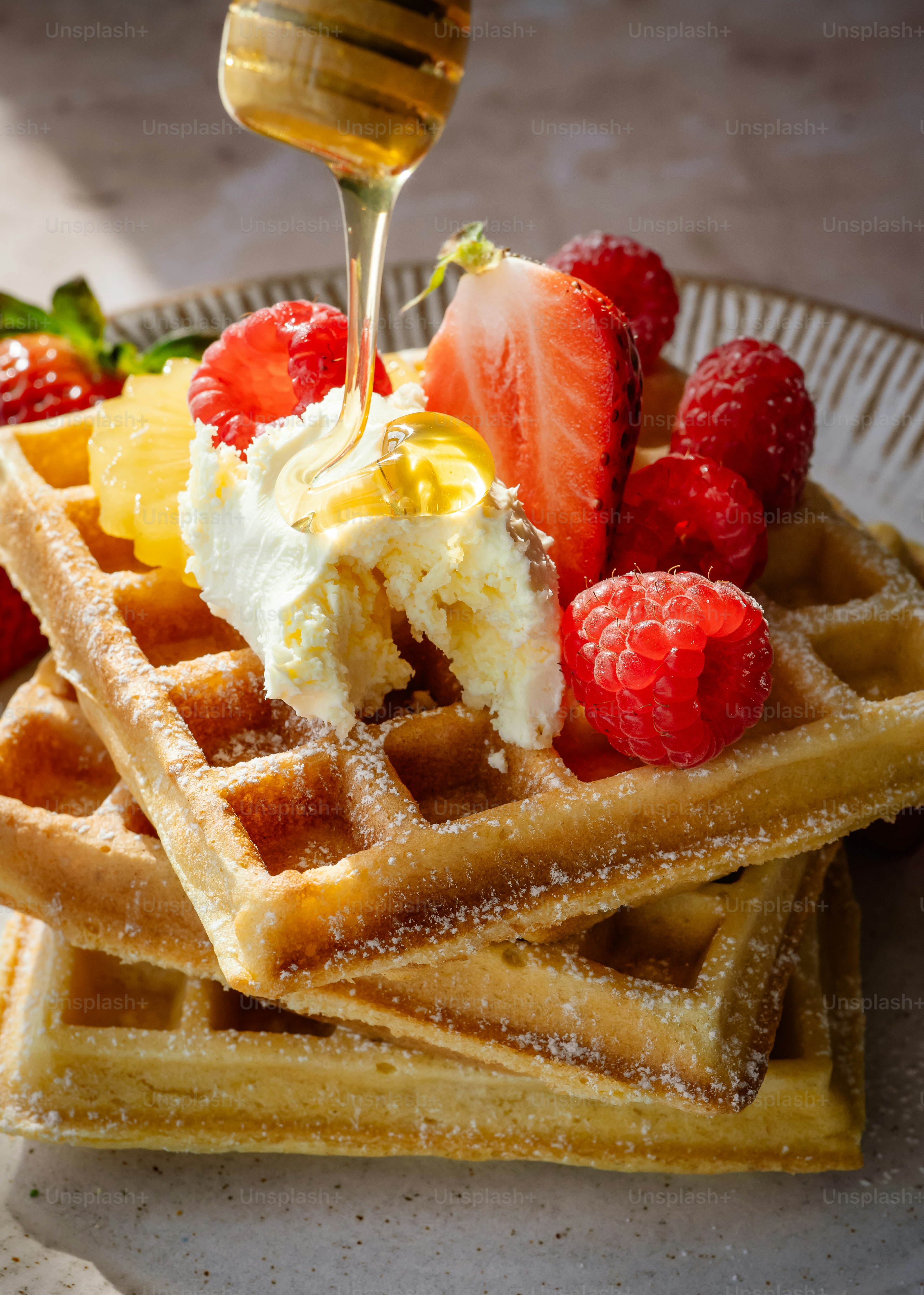 Fresh waffles topped with berries, cream, and drizzled honey