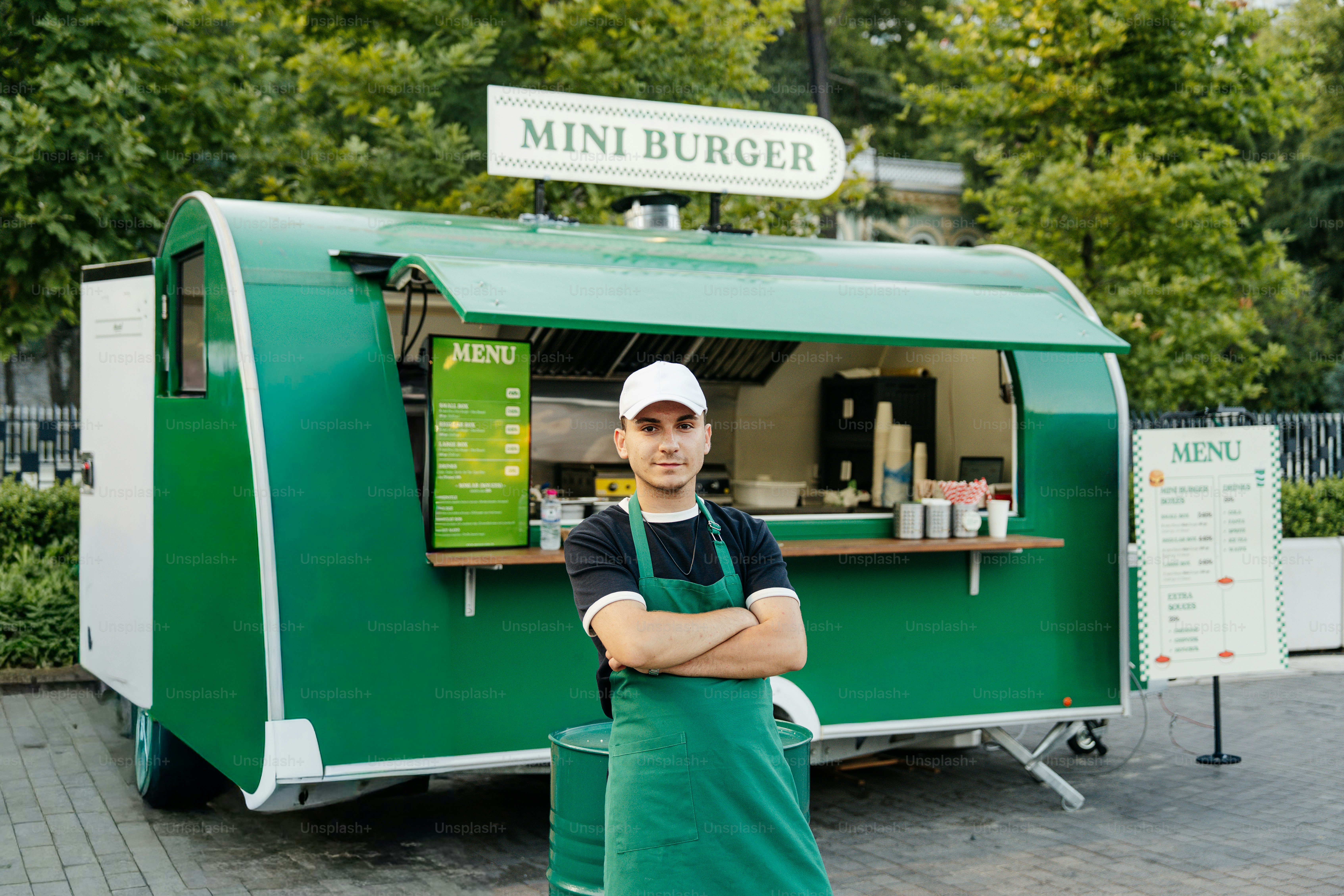 Mann mit Schürze beim grünen Mini-Burger-Foodtruck