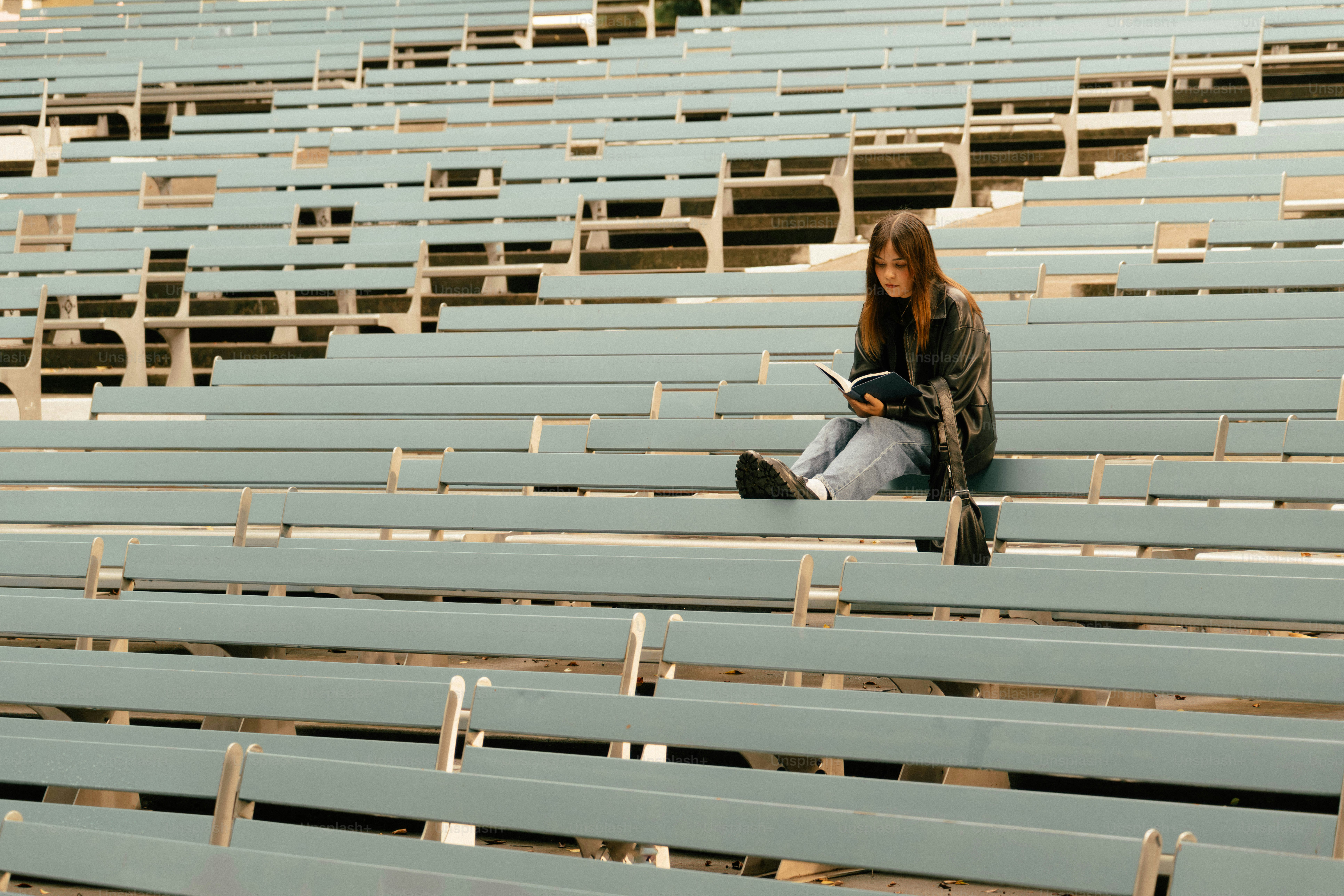 Young woman reading a book on empty bleachers