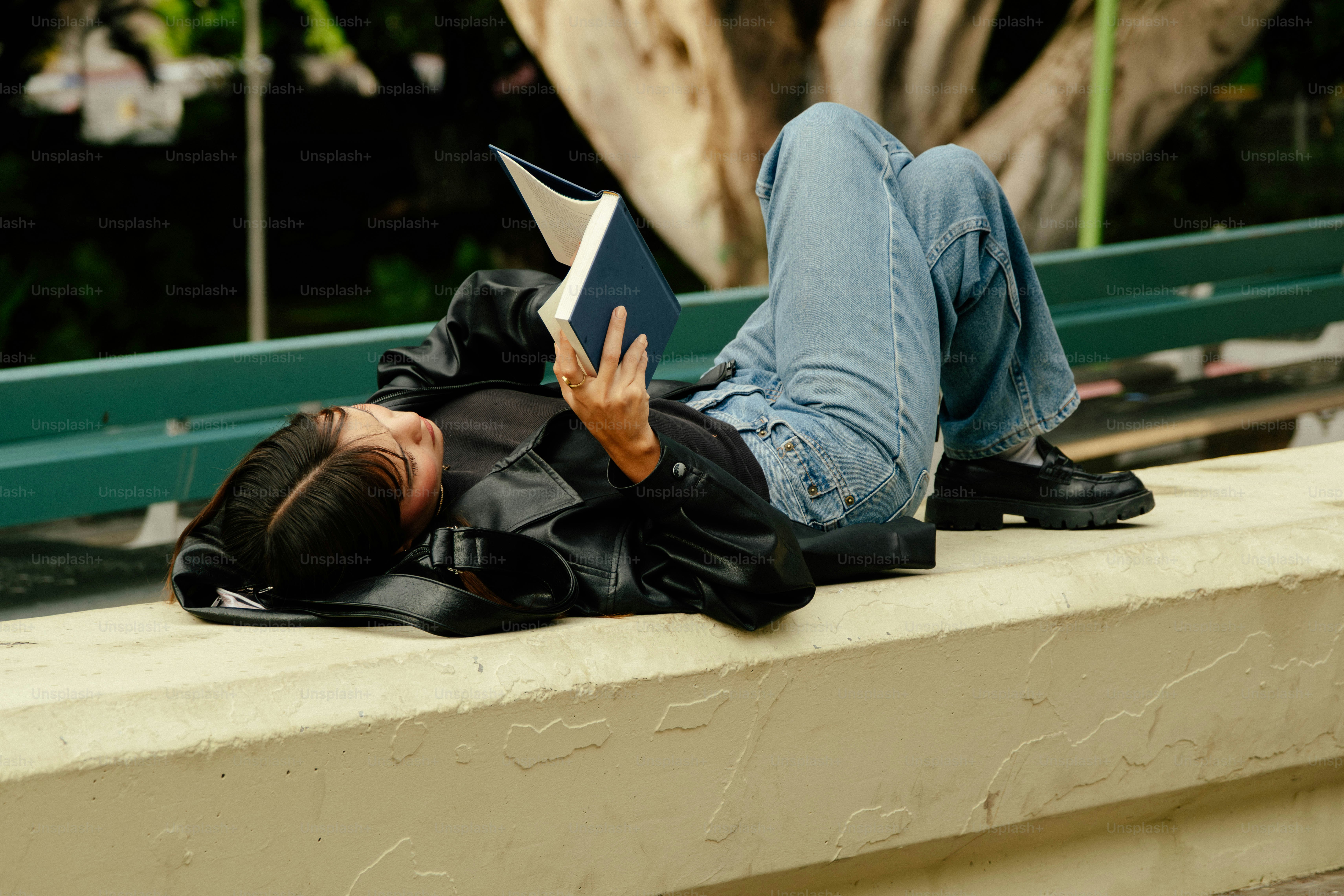 Person lying on a ledge reading a book
