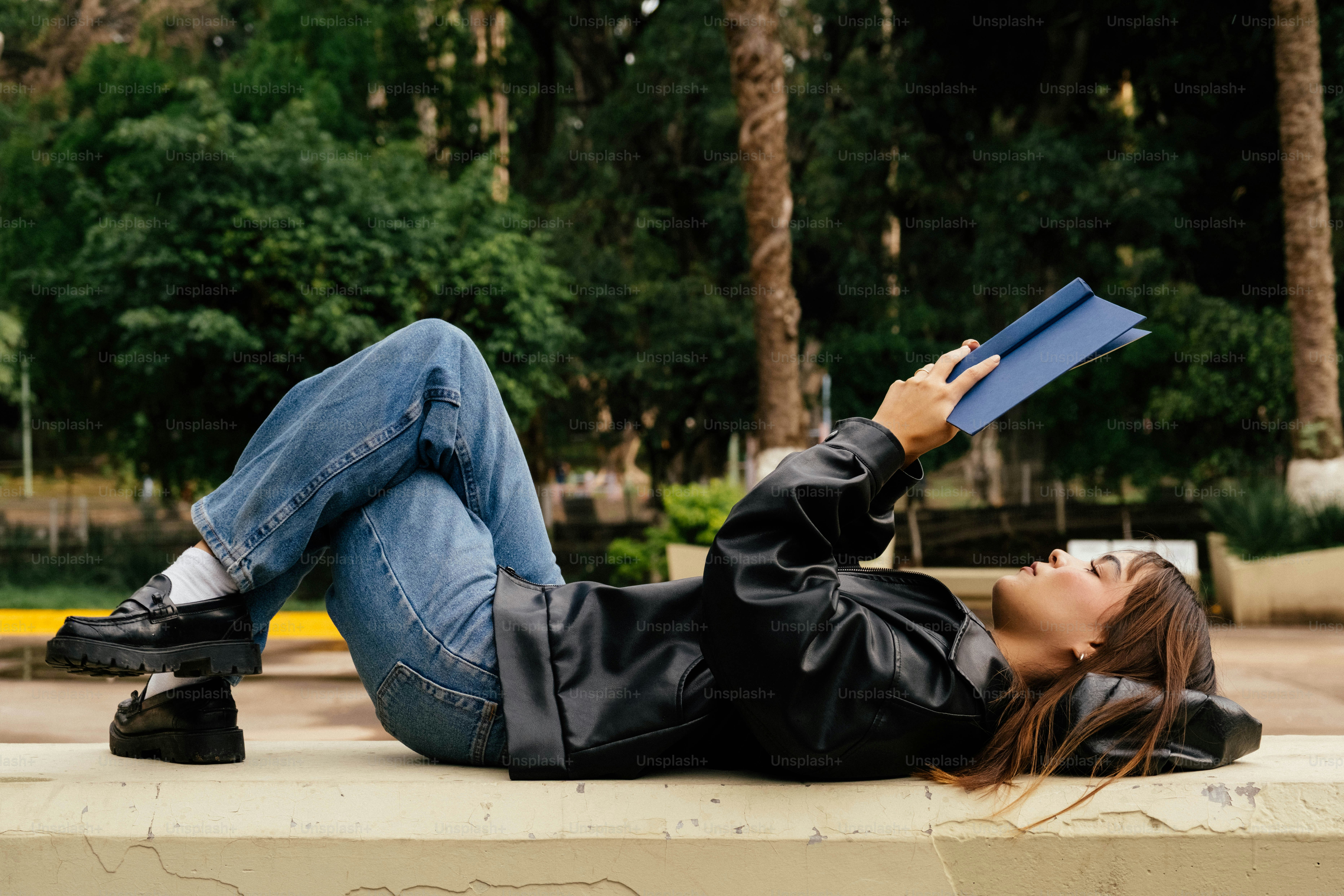 Woman lying on a bench reading a book
