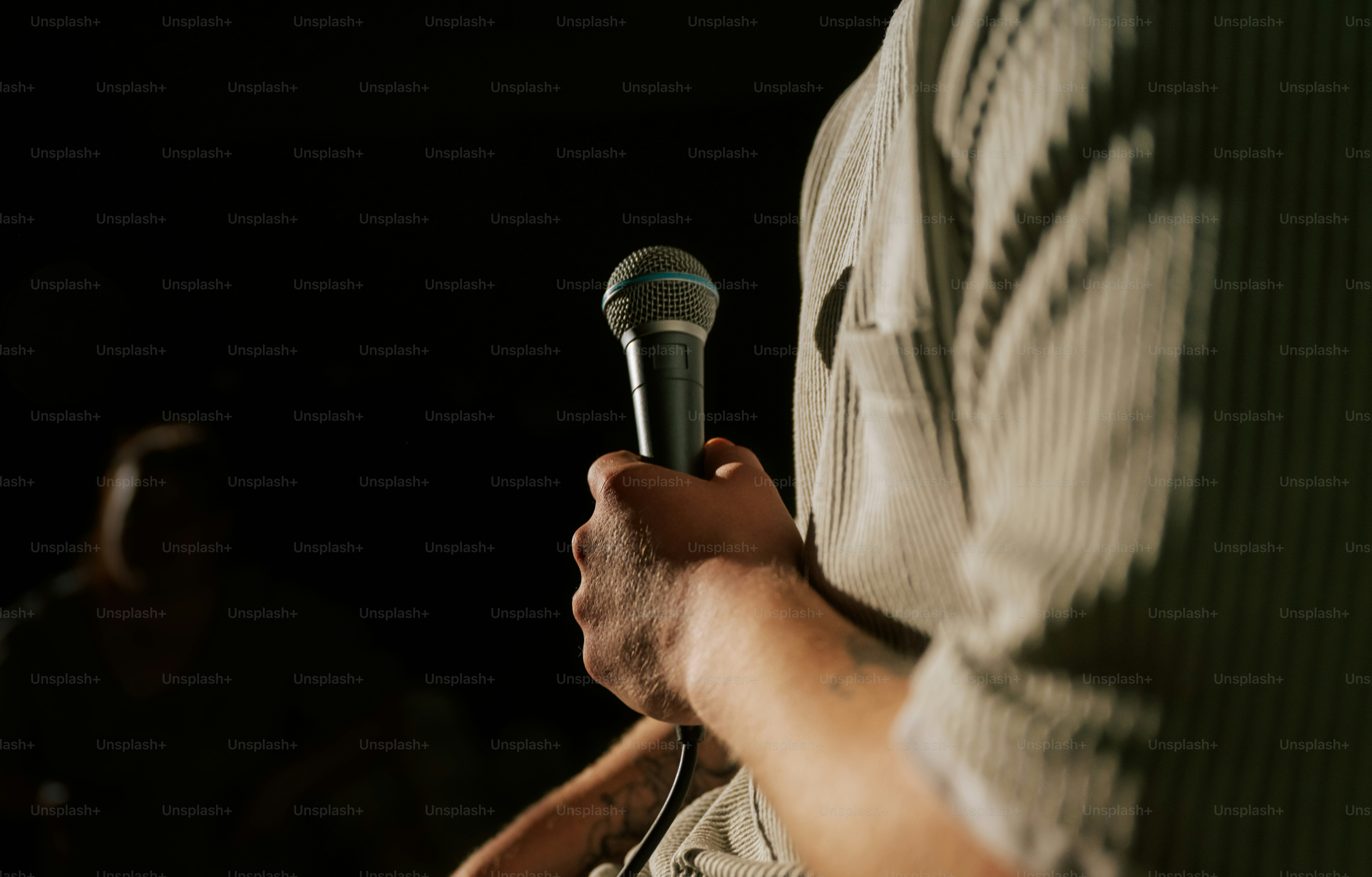 Hand holding a microphone against dark background
