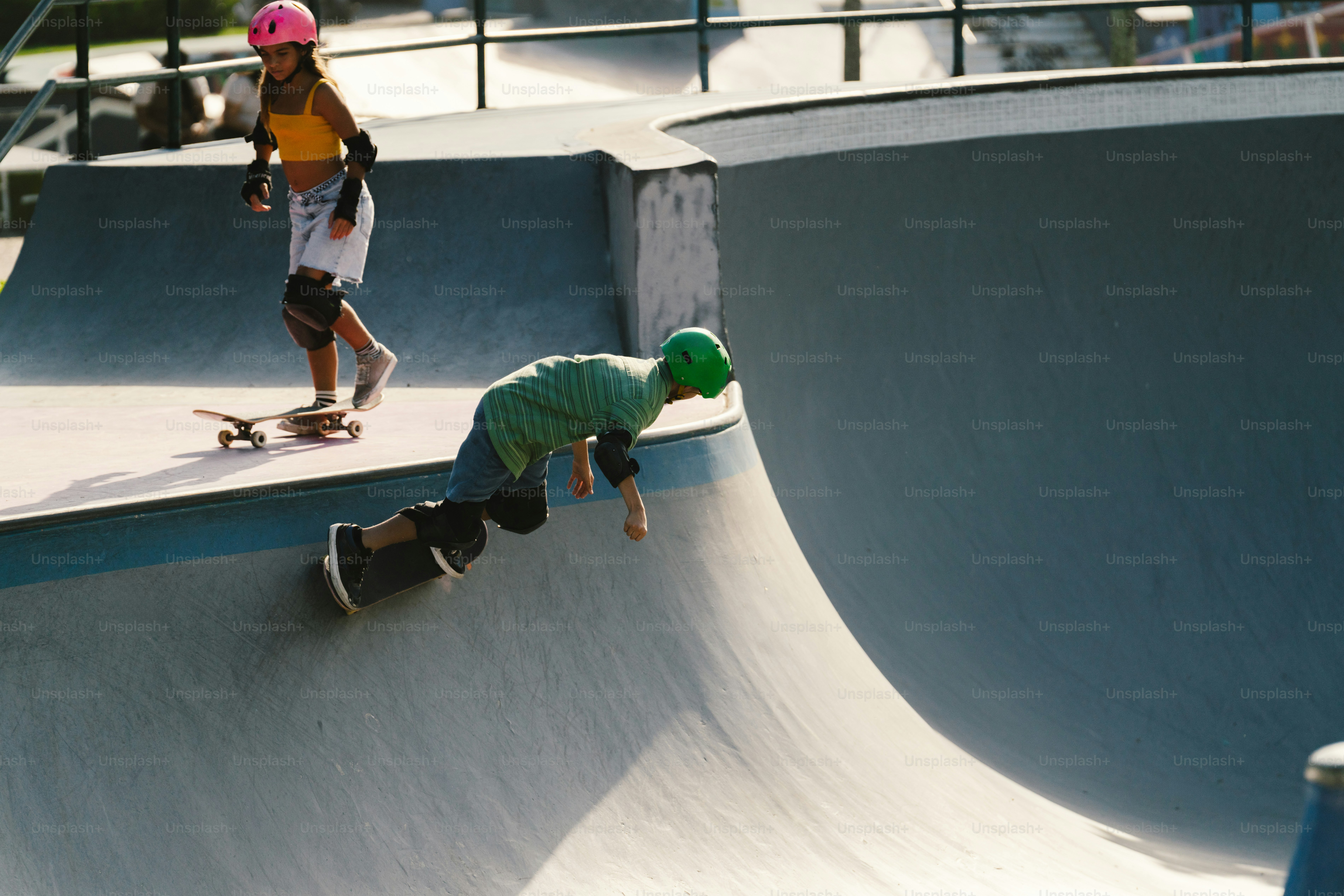 Young skateboarder falling on a ramp, another watching