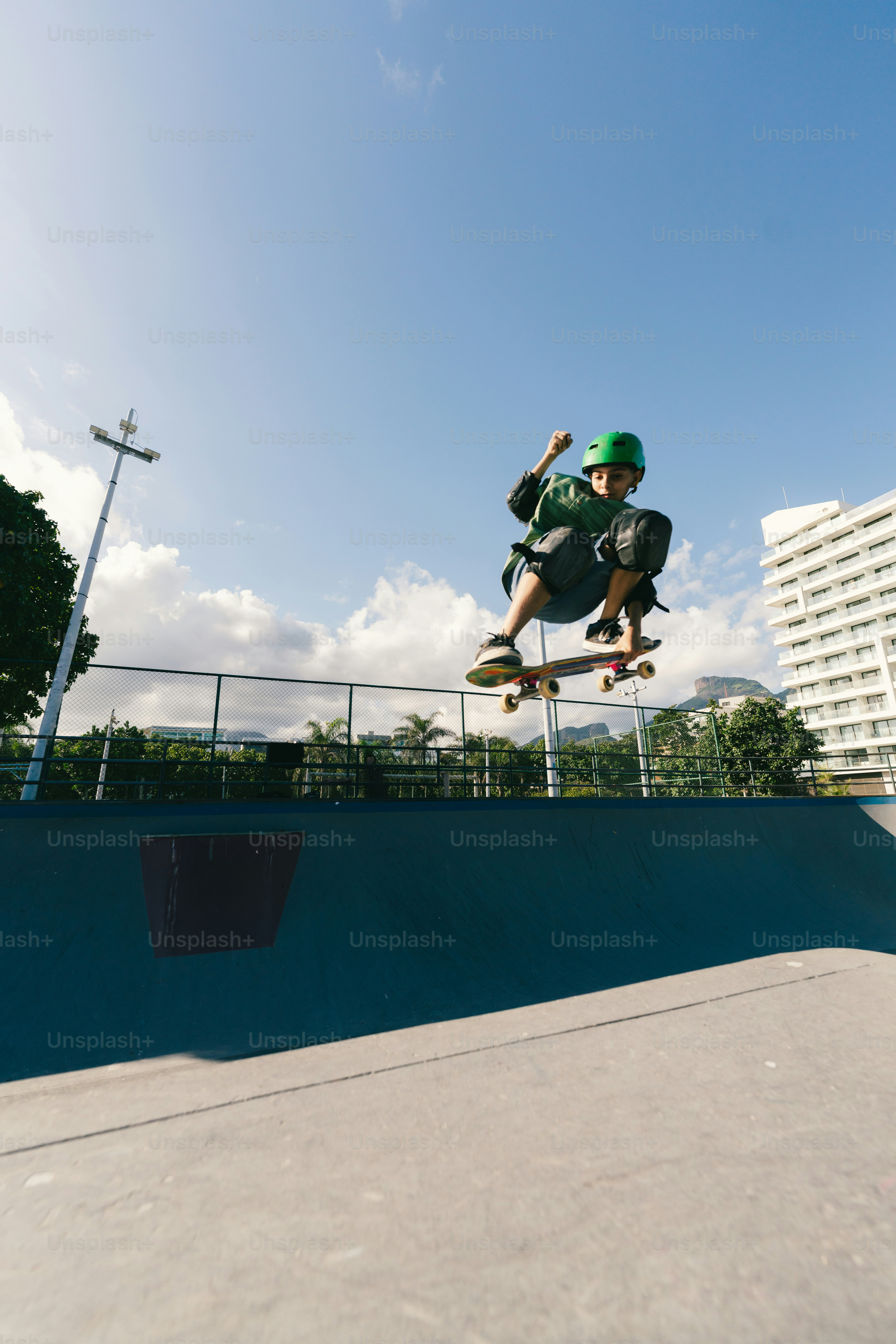 Skateboarder jumping high in a sunny skatepark