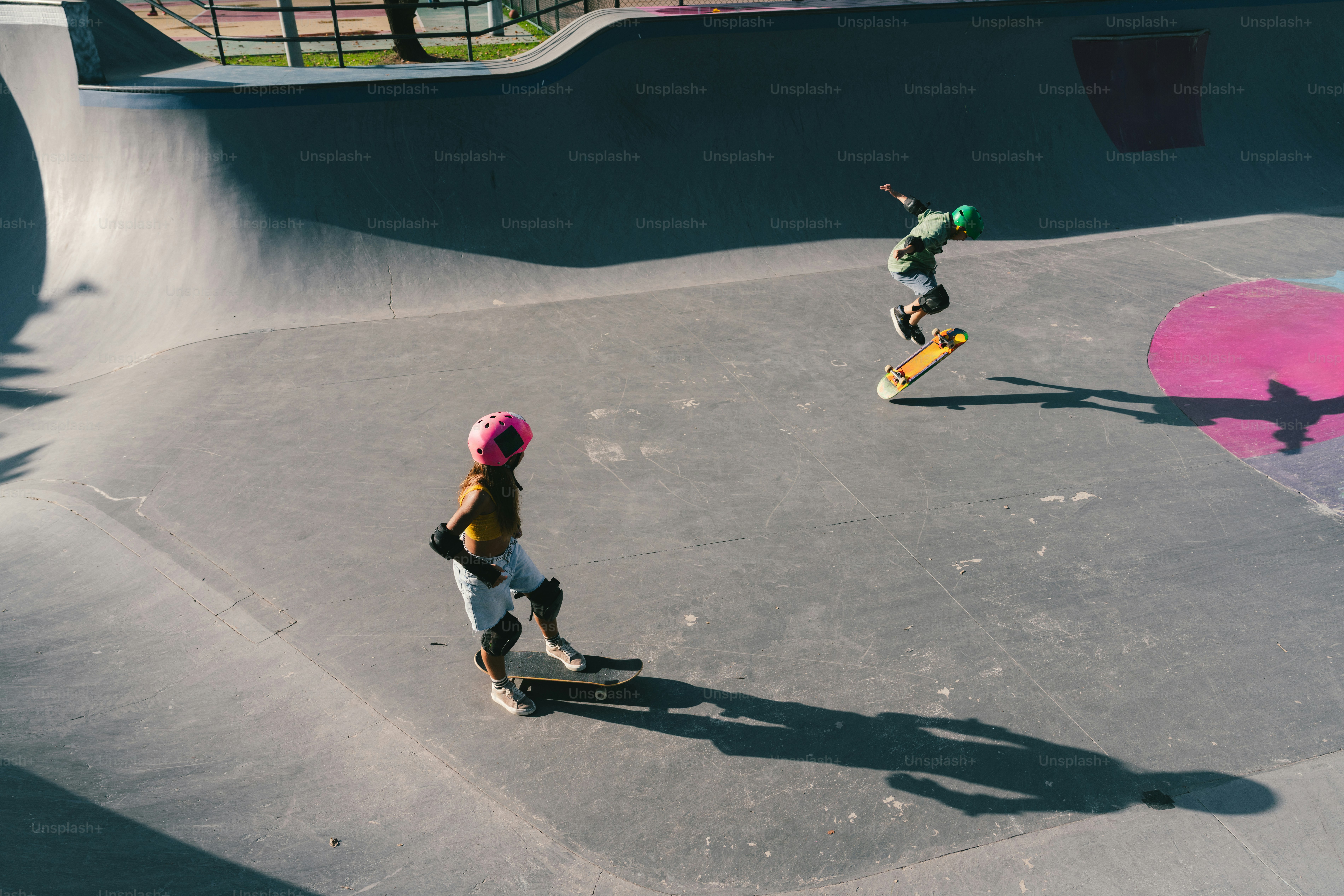 Skateboarders performing tricks in a sunny concrete skate park