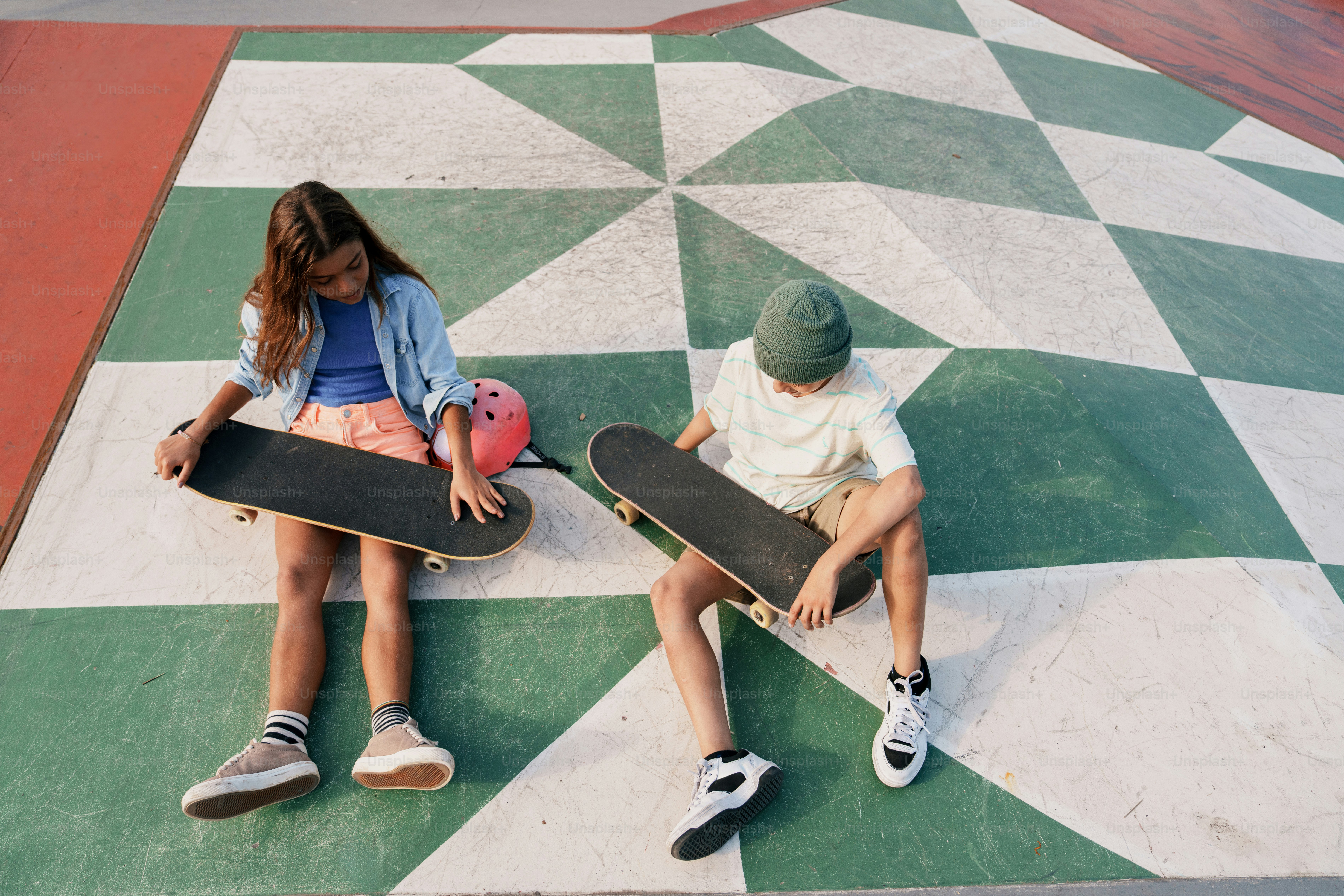 Young skaters sitting with boards on patterned ground