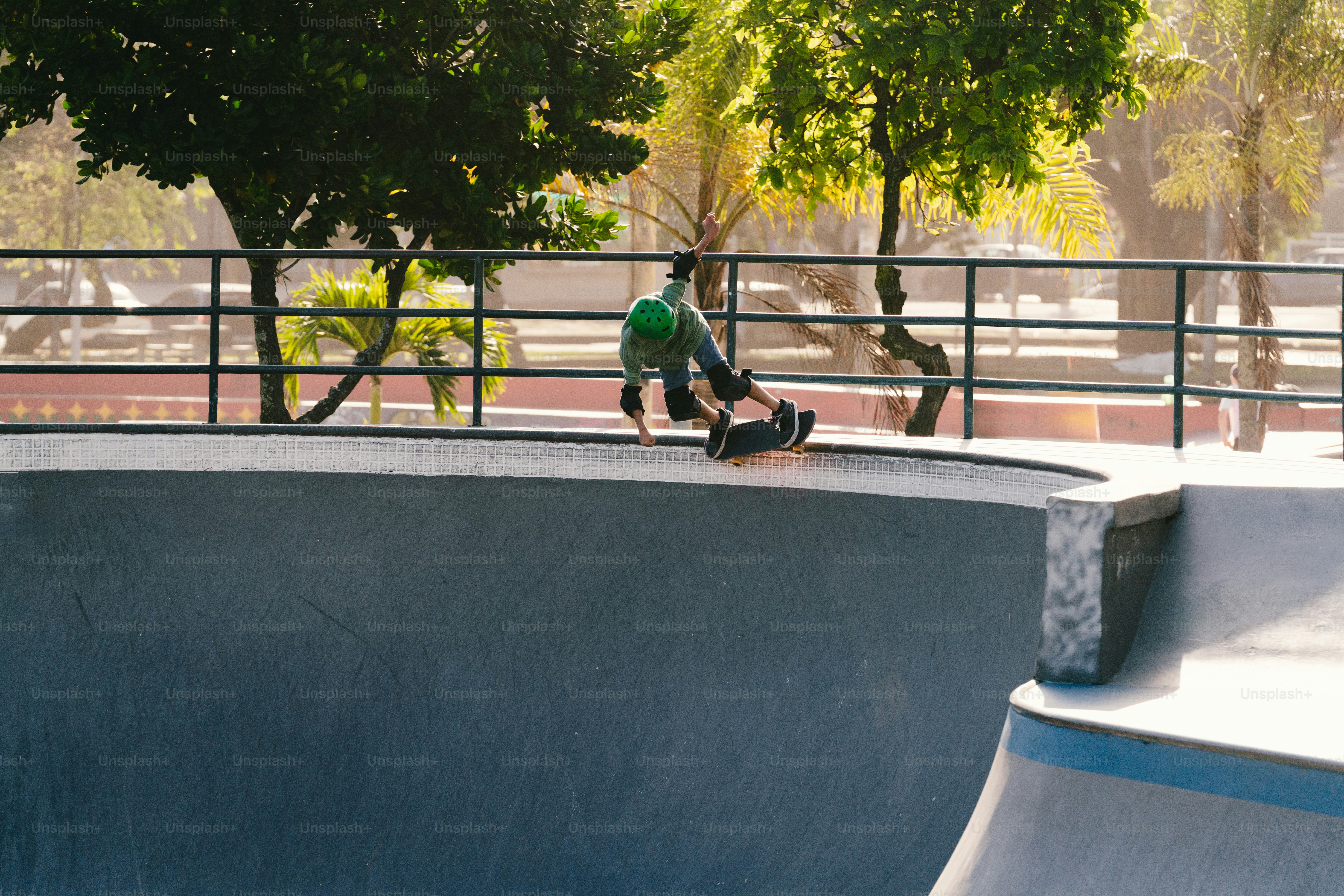 Skateboarder falling off board in concrete skatepark bowl