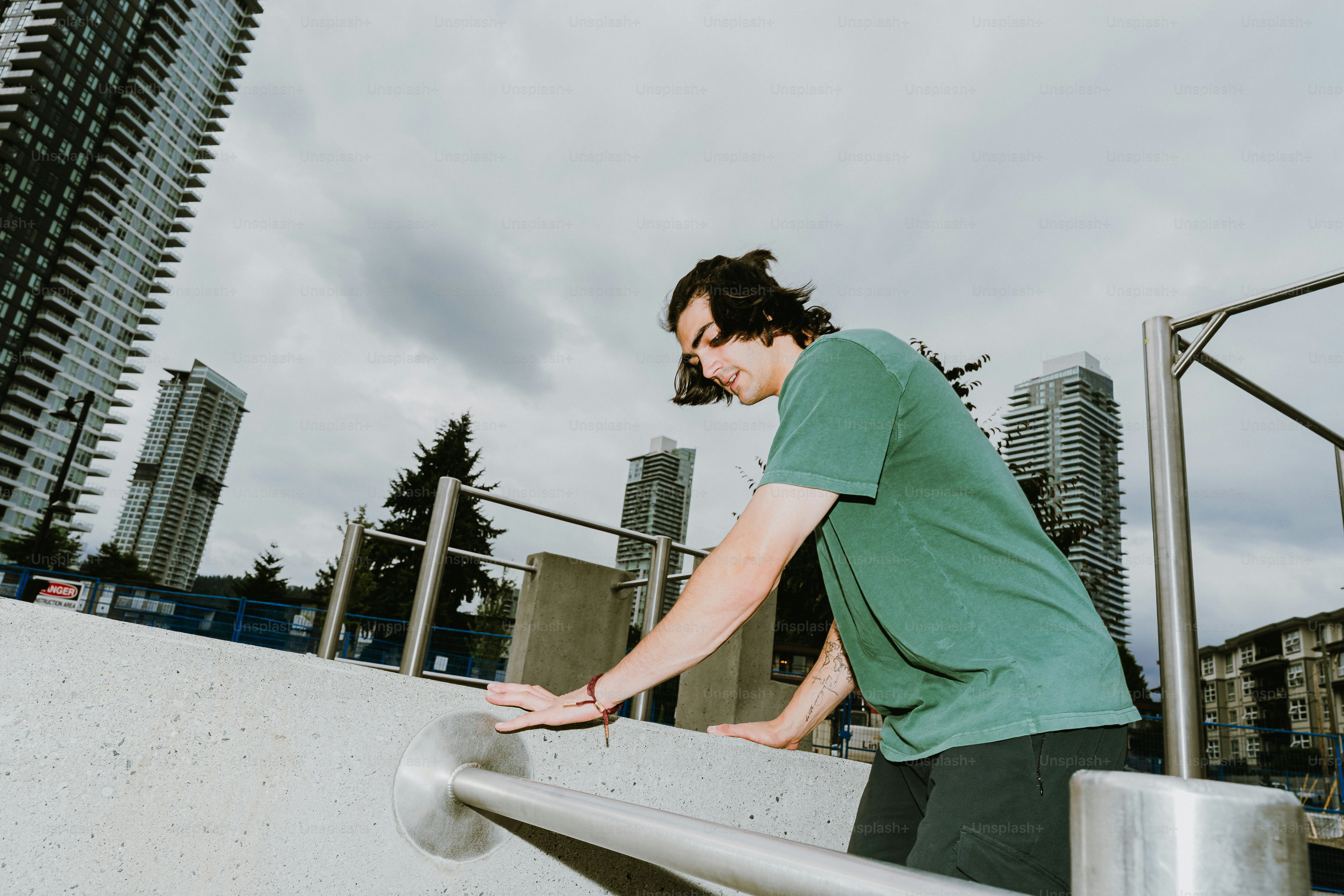 Young man on urban barrier with city buildings
