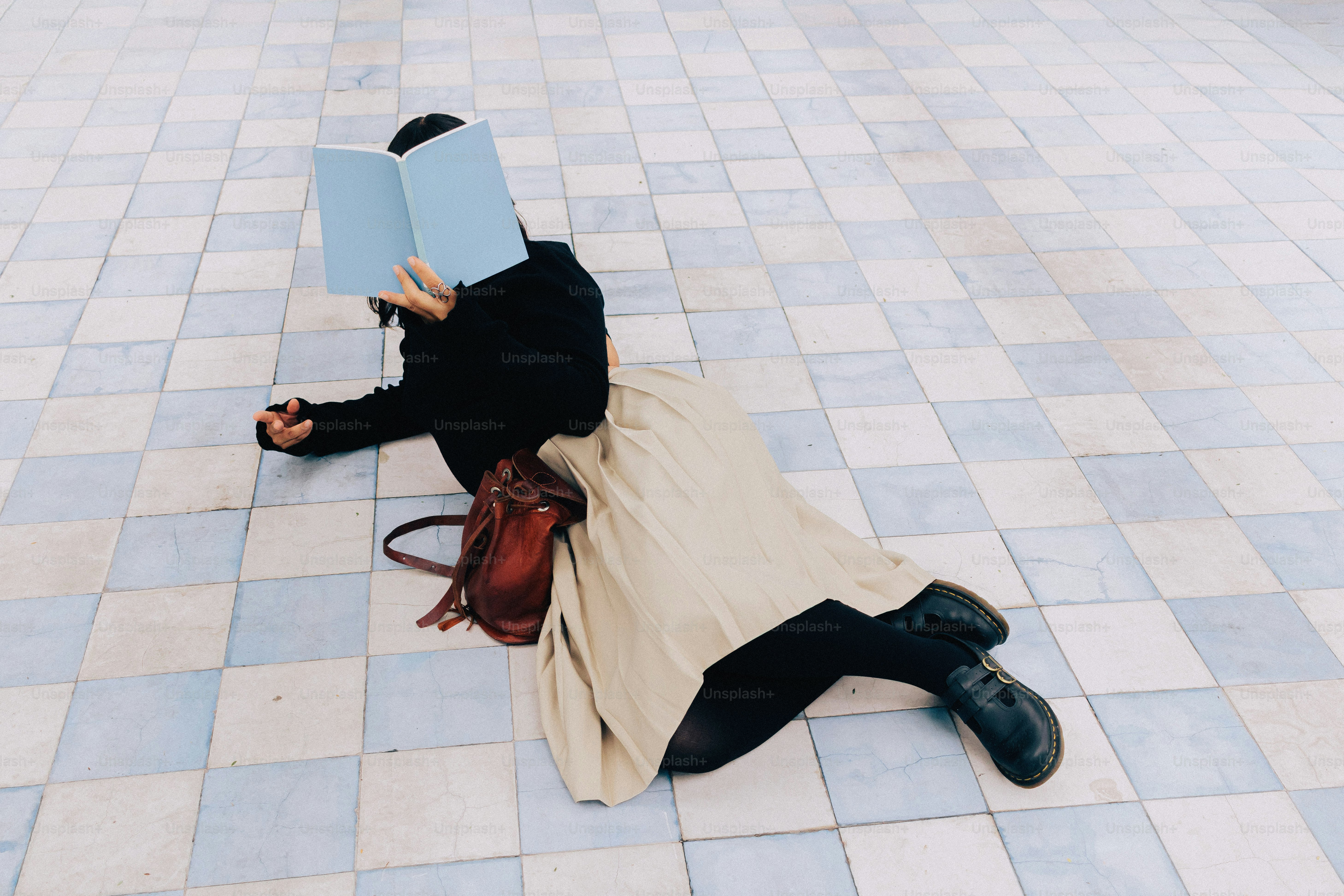 Person, die ein Buch liest, auf karierten Fliesenboden sitzt