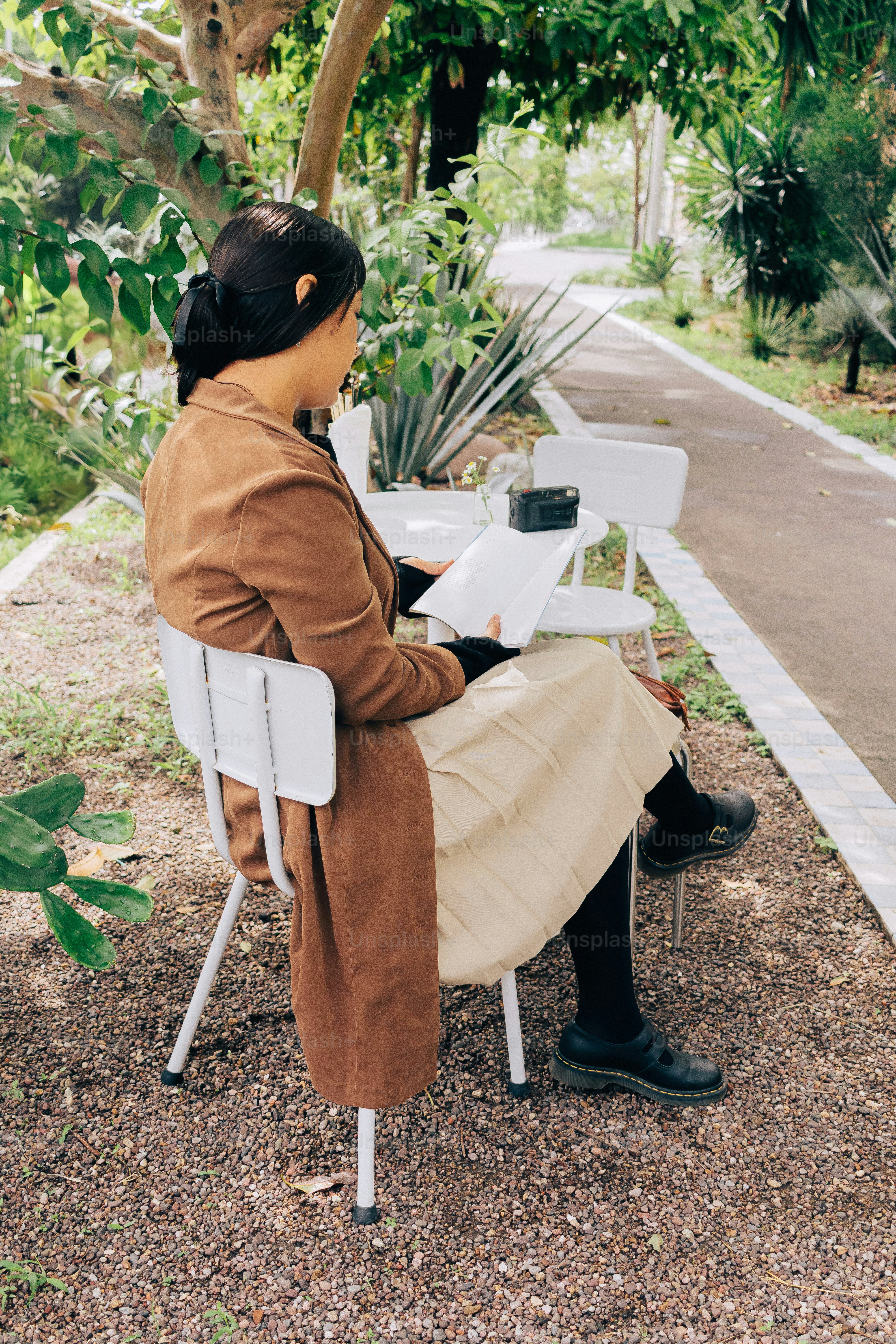 Frau liest Buch am Außentisch im Garten