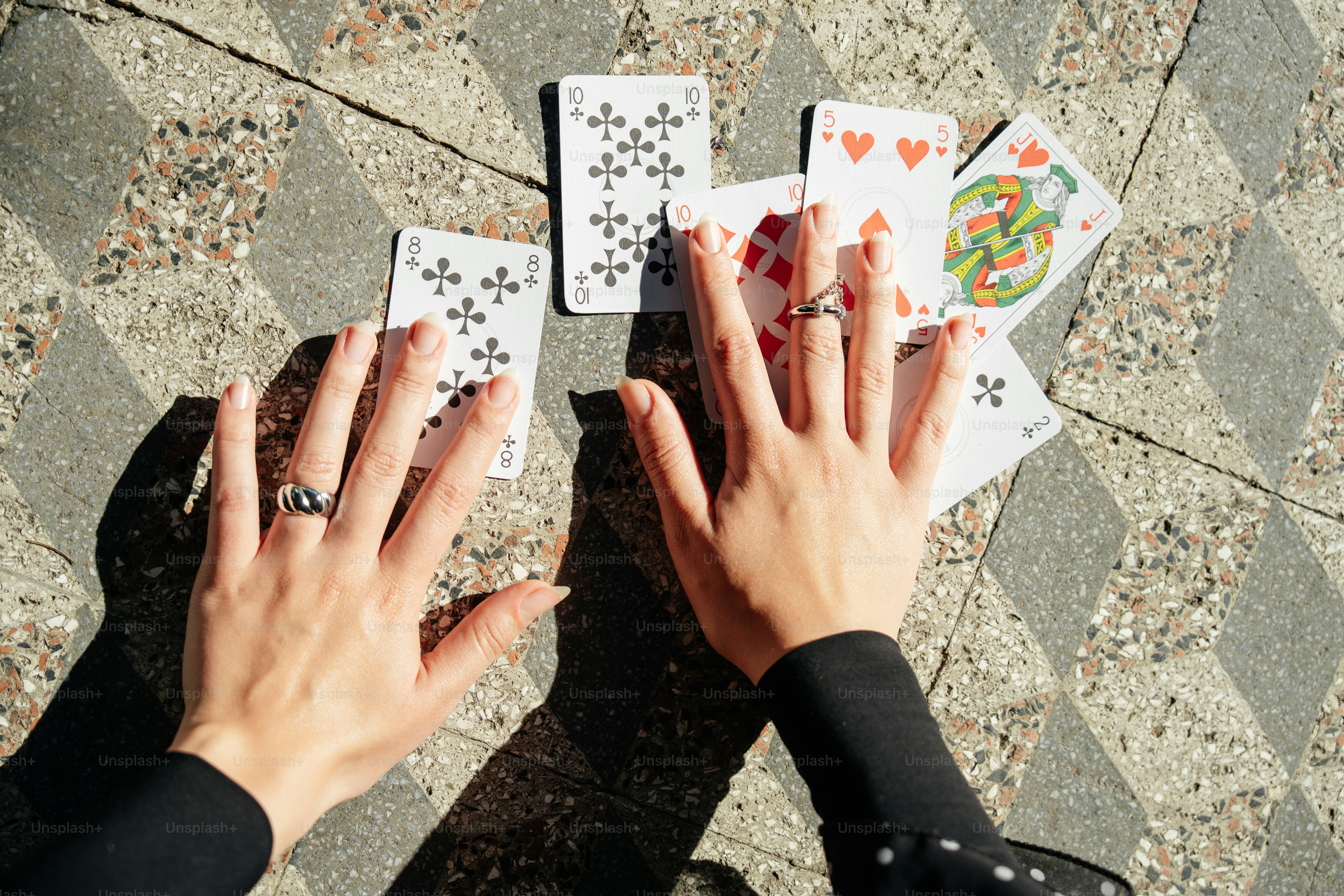 Hands reaching for playing cards on a patterned ground