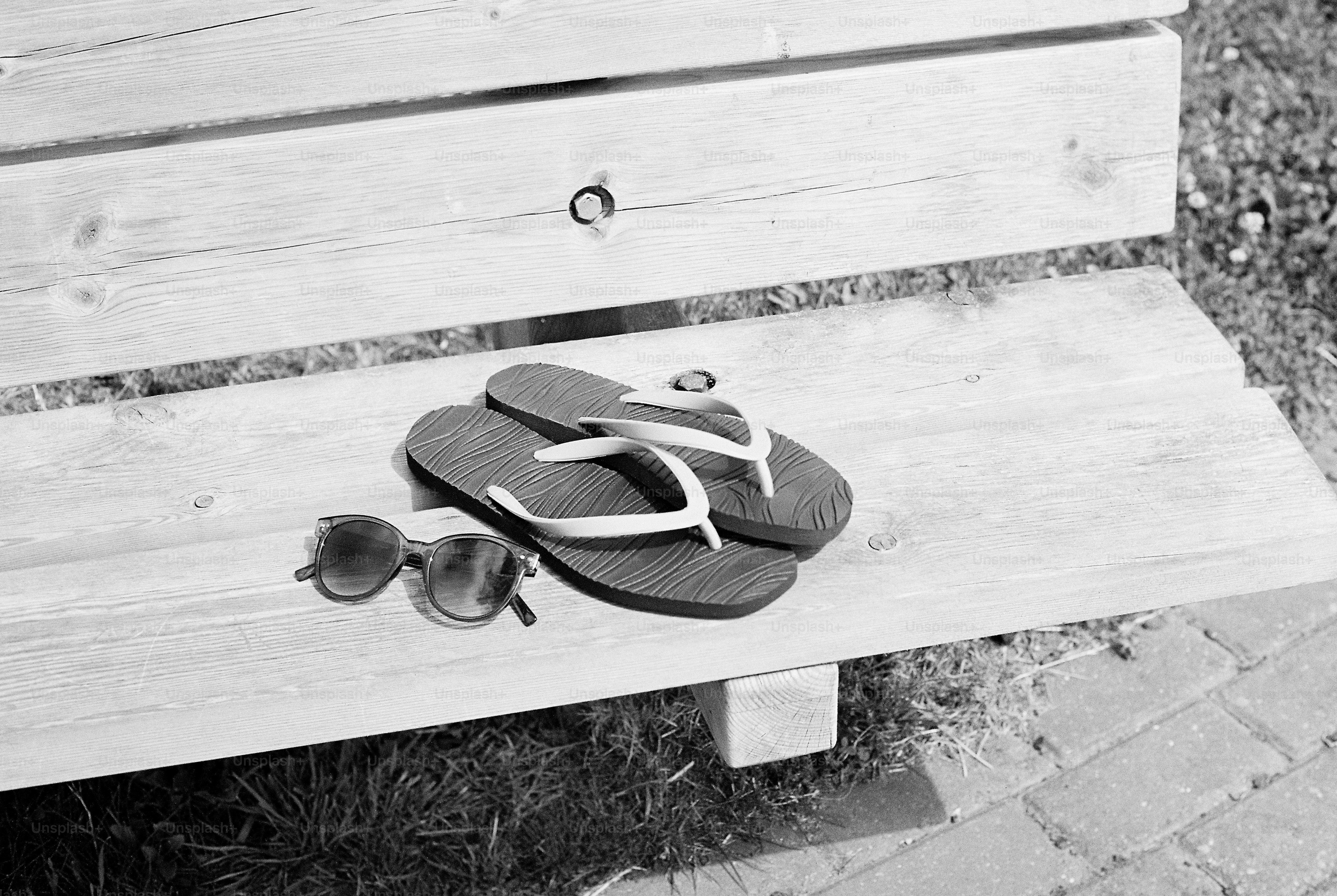 Flip-flops and sunglasses resting on a wooden bench