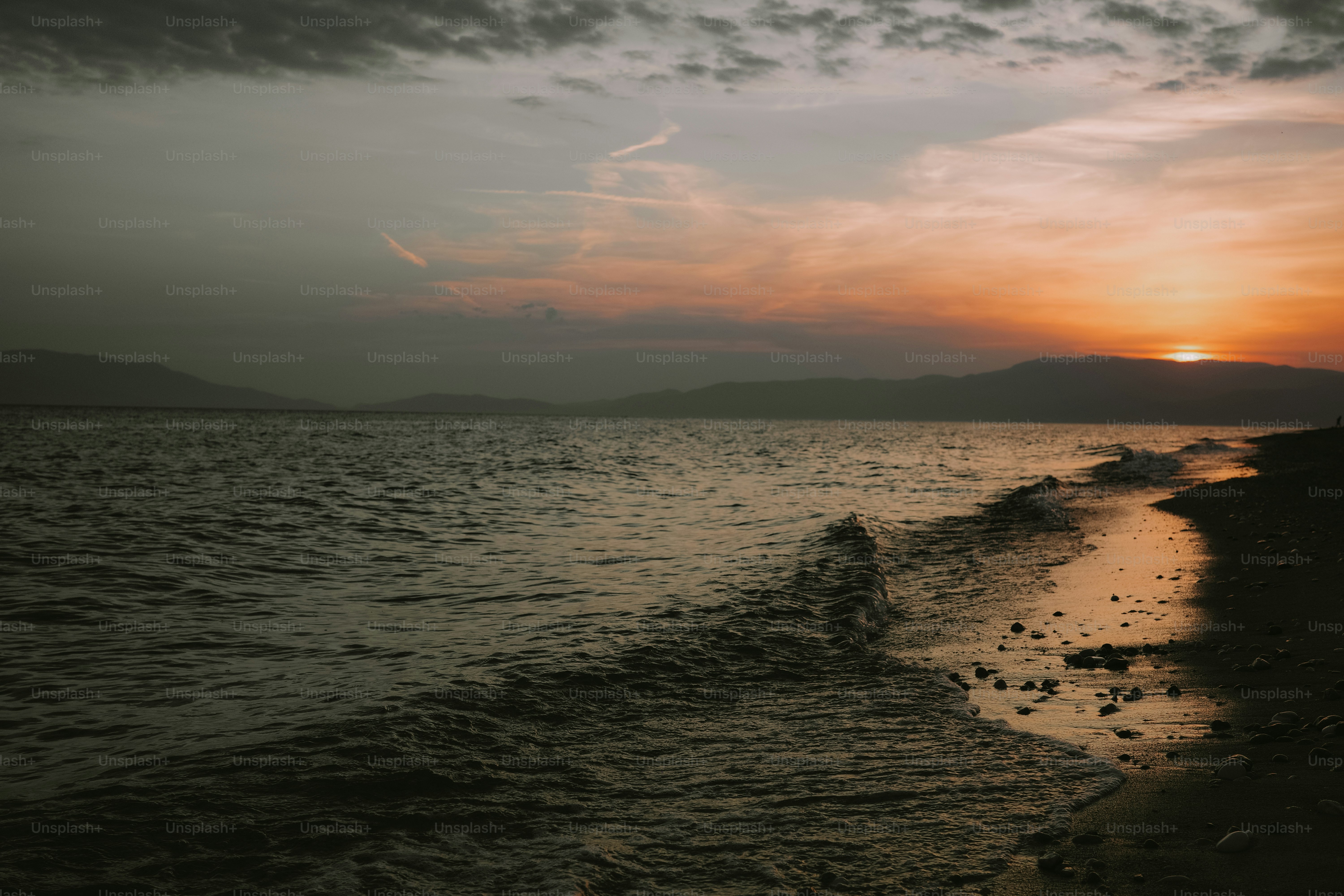 Sunset glow over water, waves on dark shore