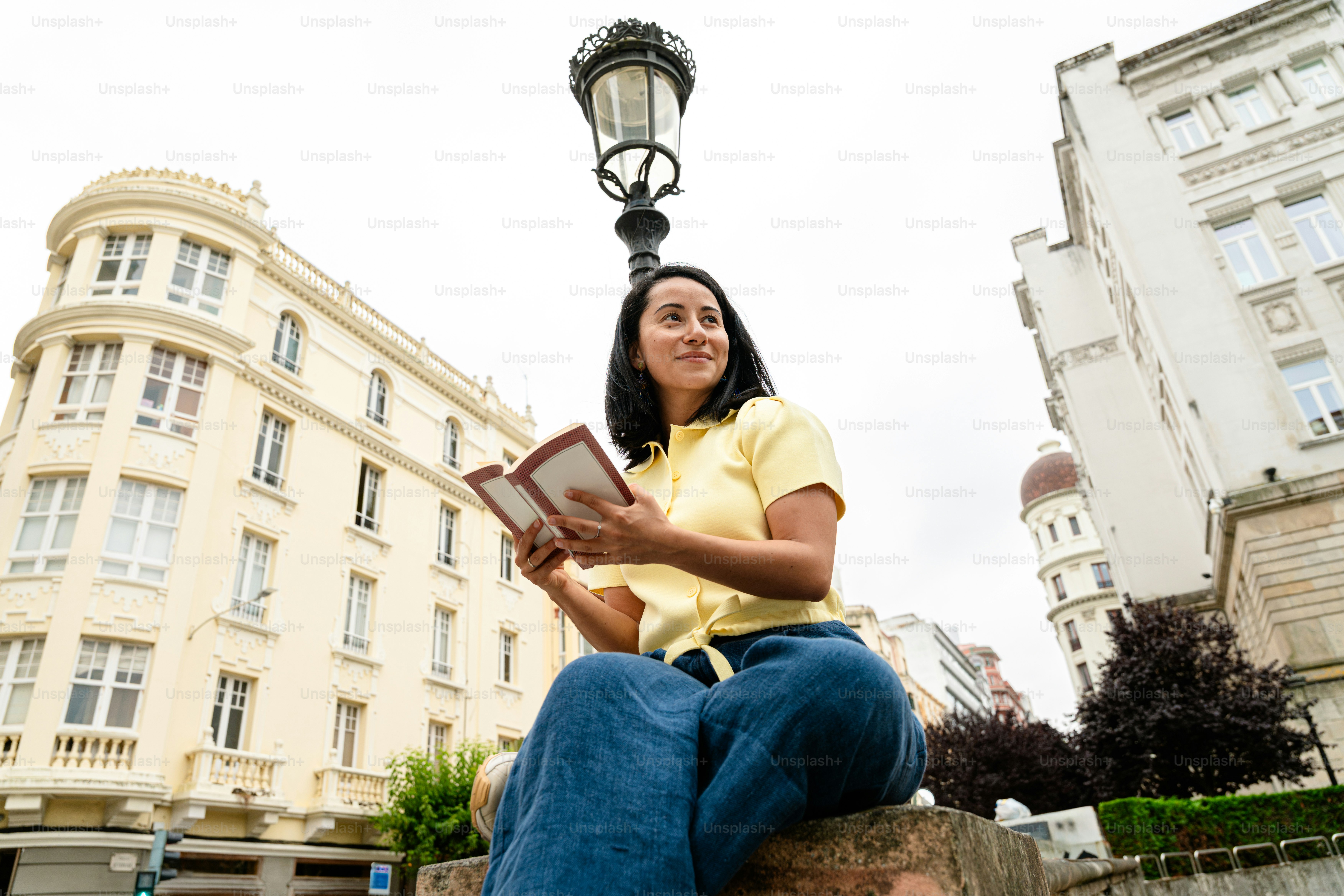 Woman holding book, smiling under city street lamp
