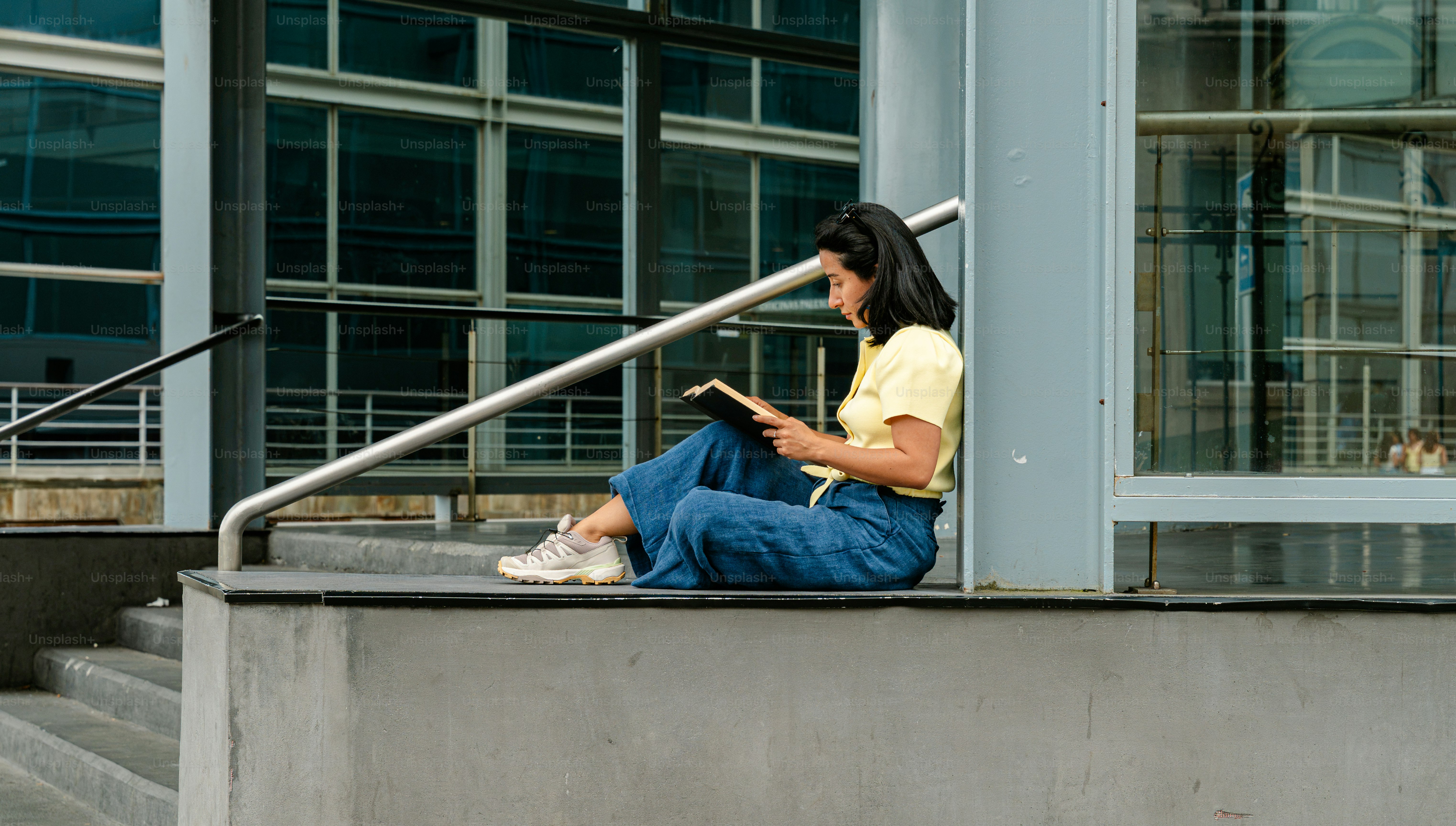 Young woman reading book on steps outside building