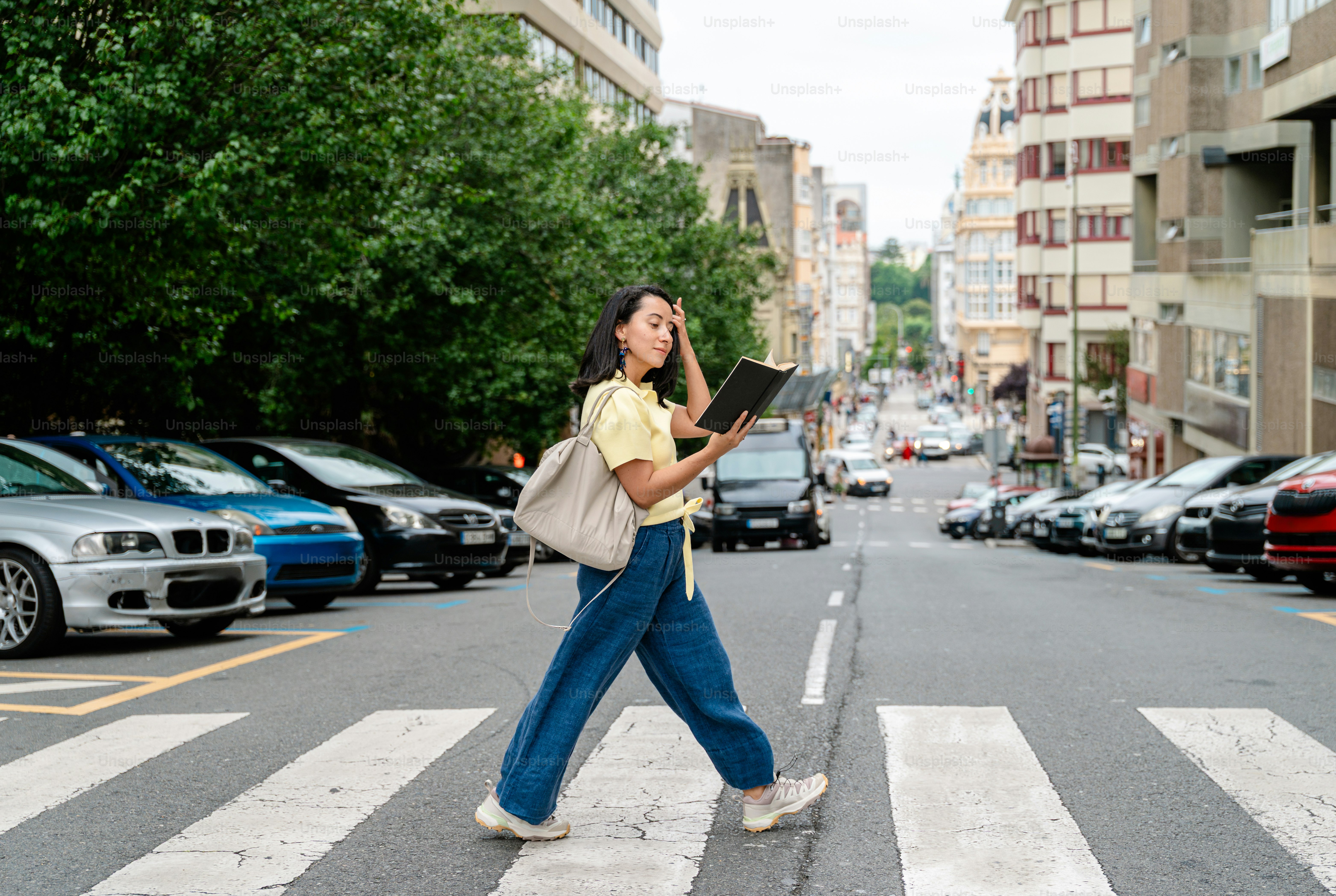 Woman crossing street reading a book