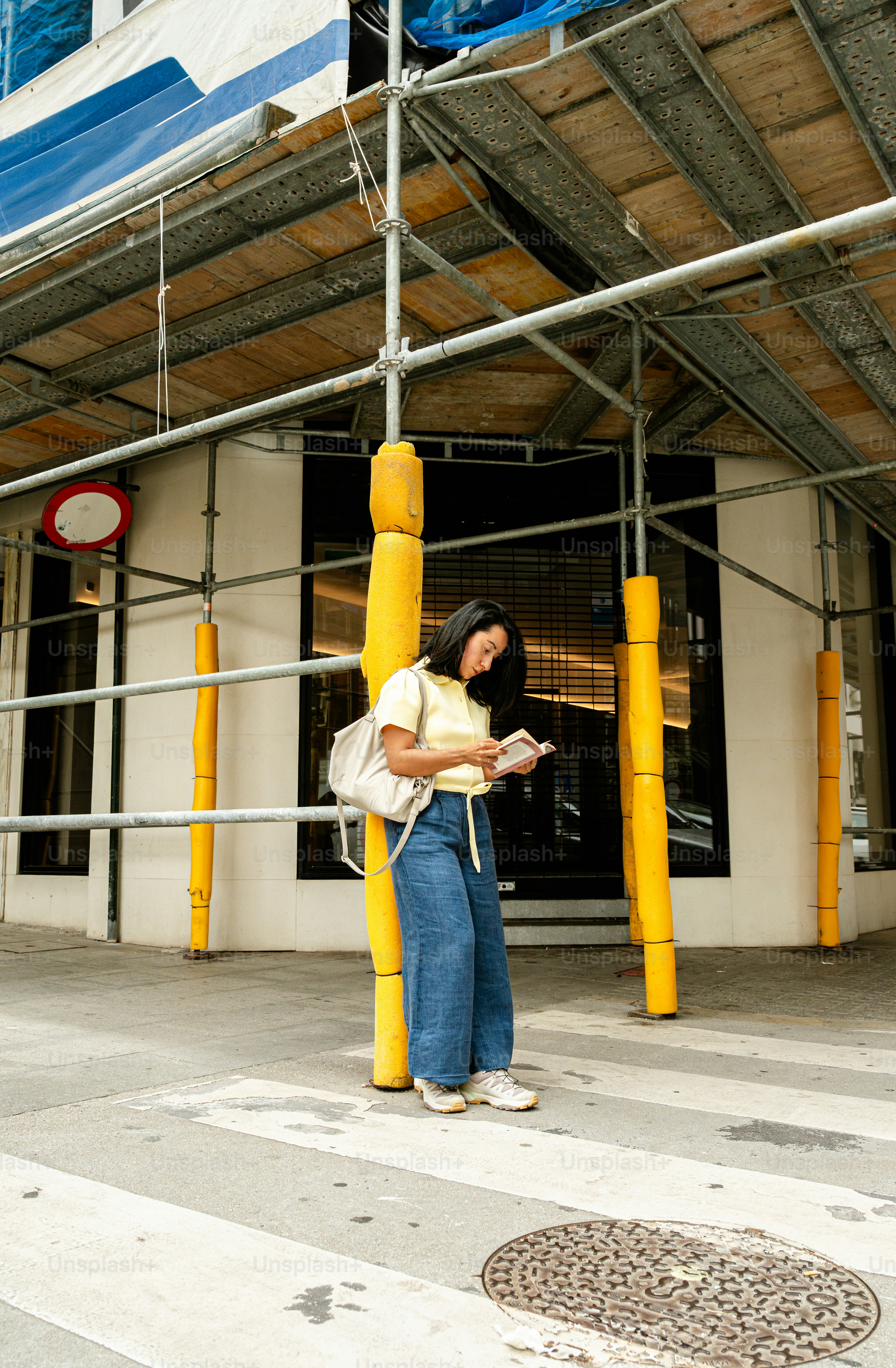 Woman checking phone under construction scaffolding