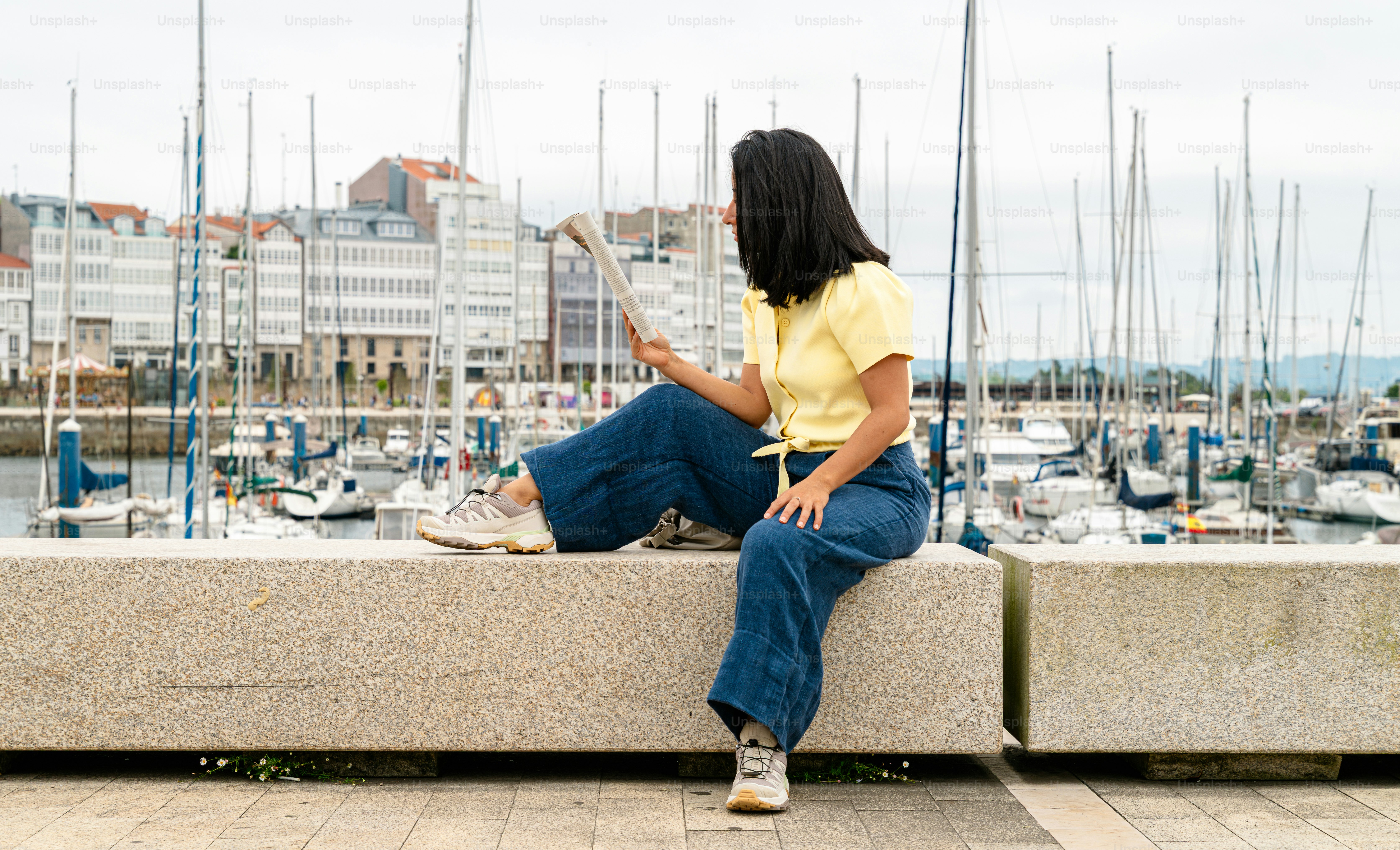 Woman looking at paper by marina with sailboats