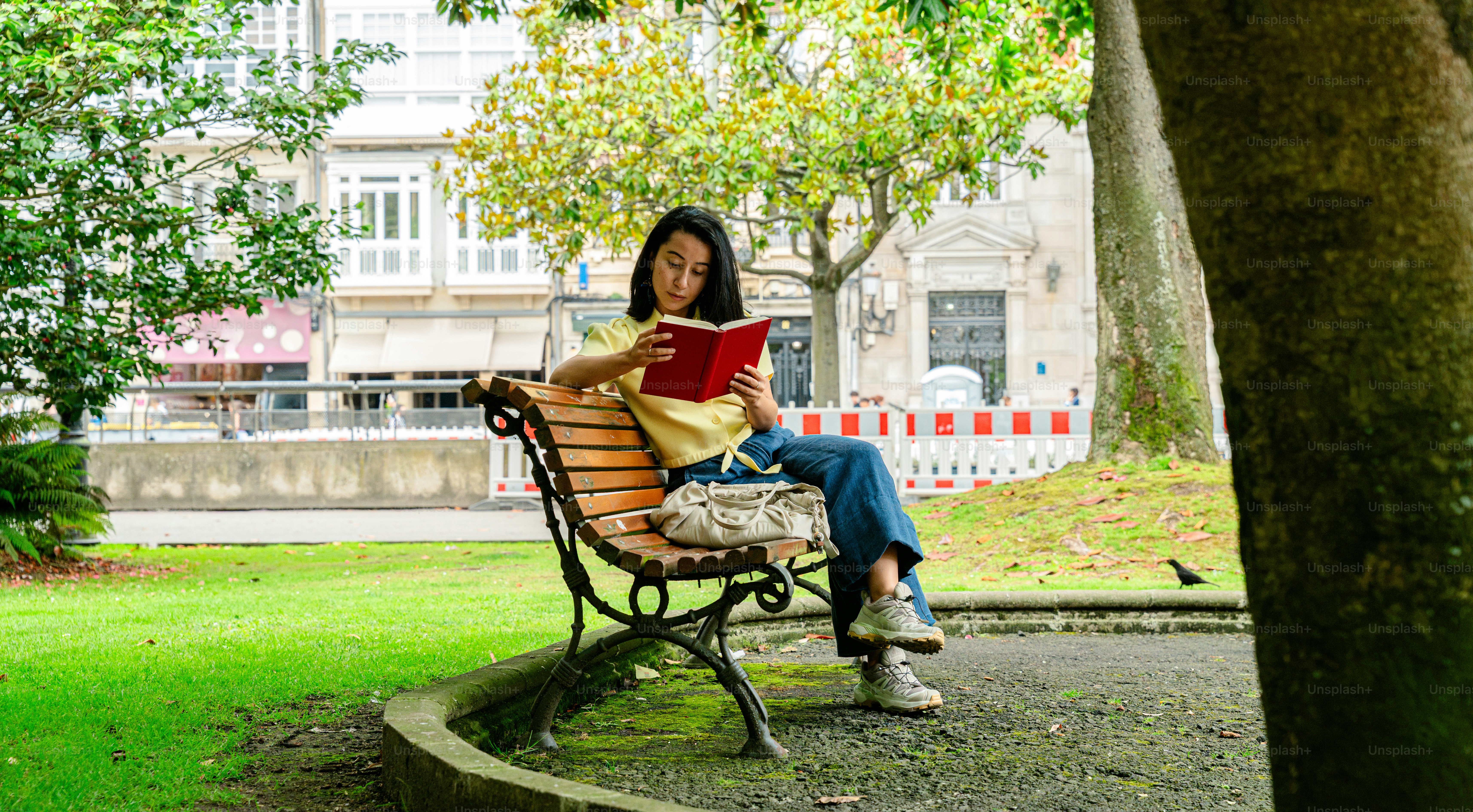 Young woman reading book on park bench
