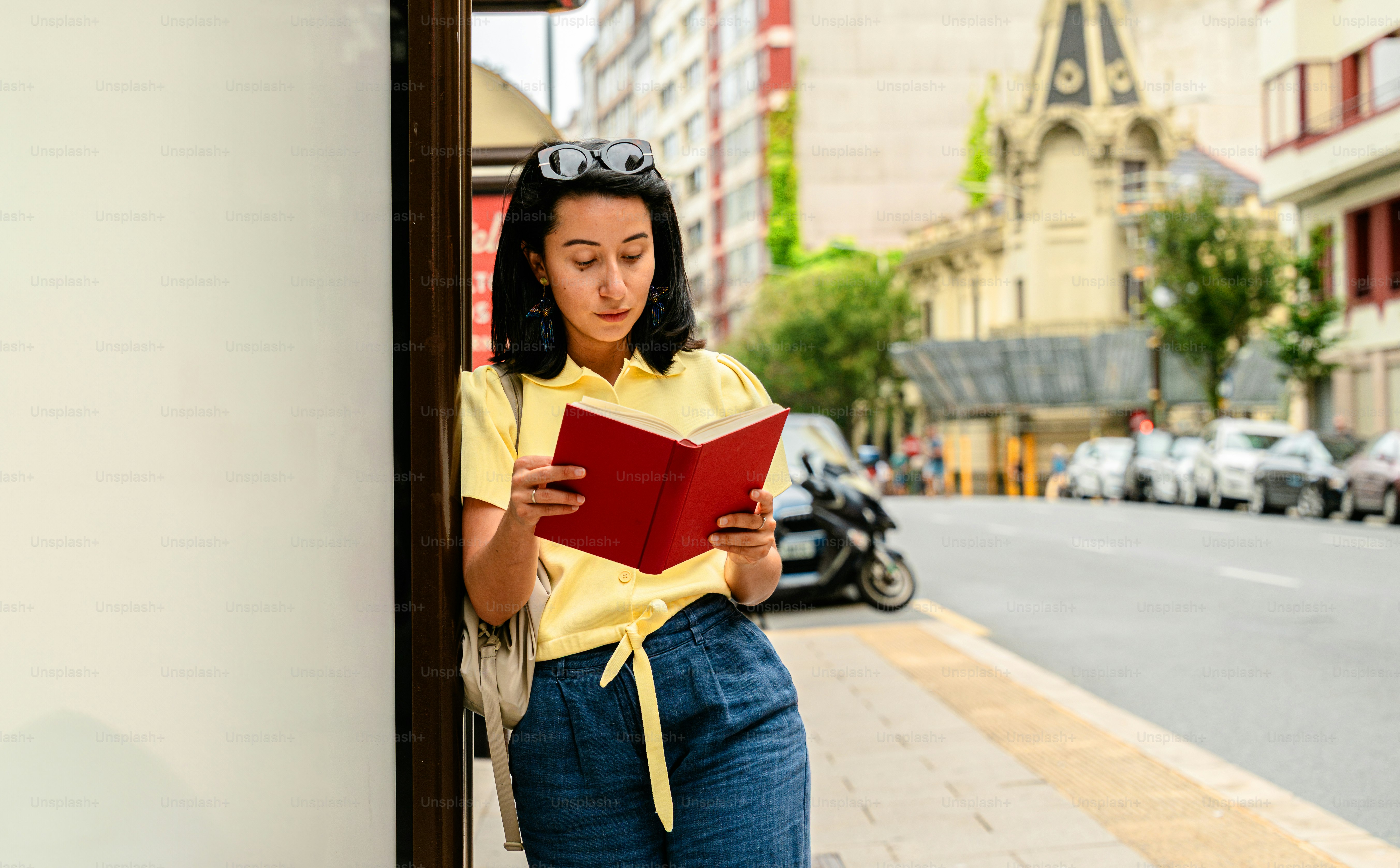 Woman reading red book on city street