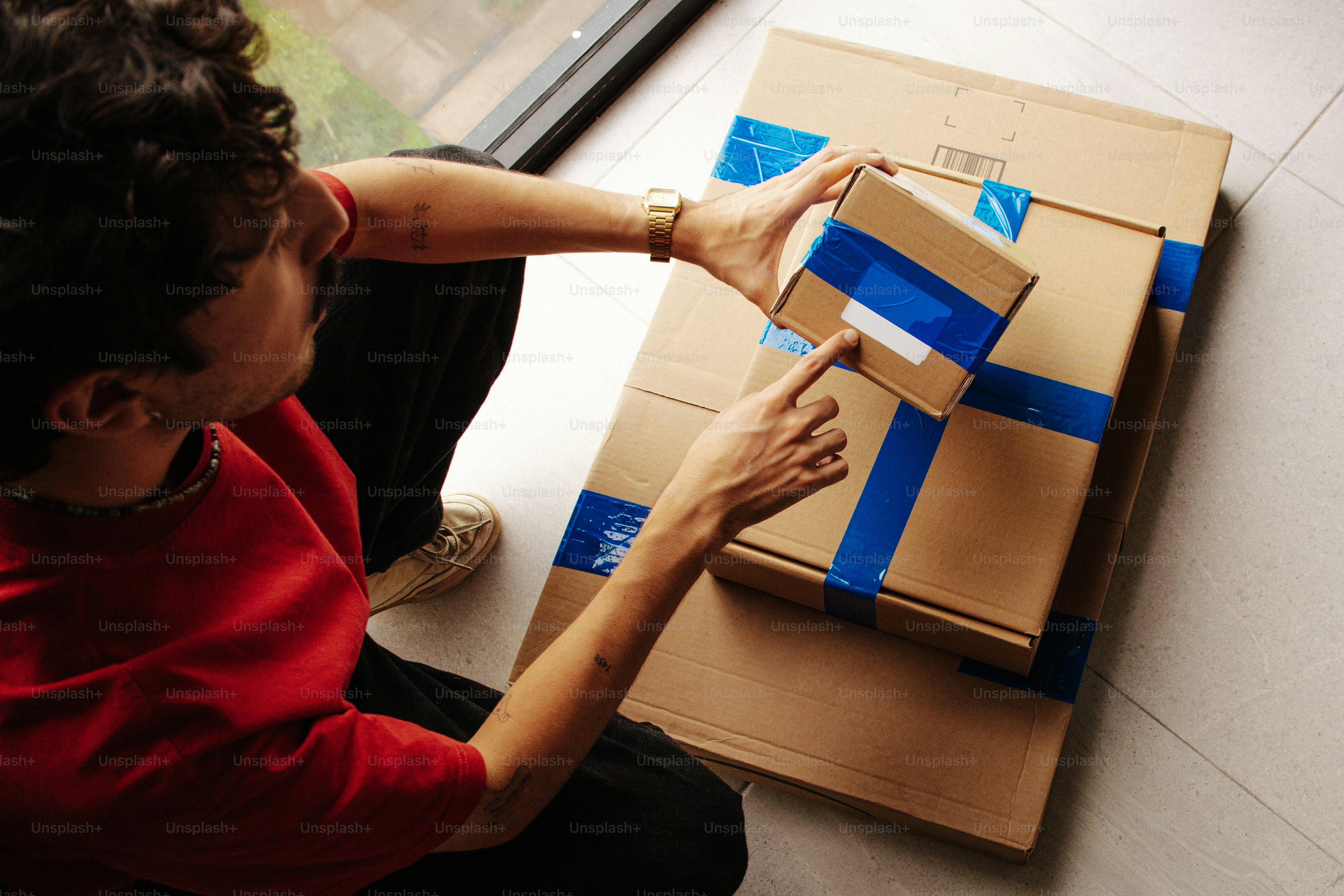 Person inspecting a small cardboard parcel while preparing it for shipment