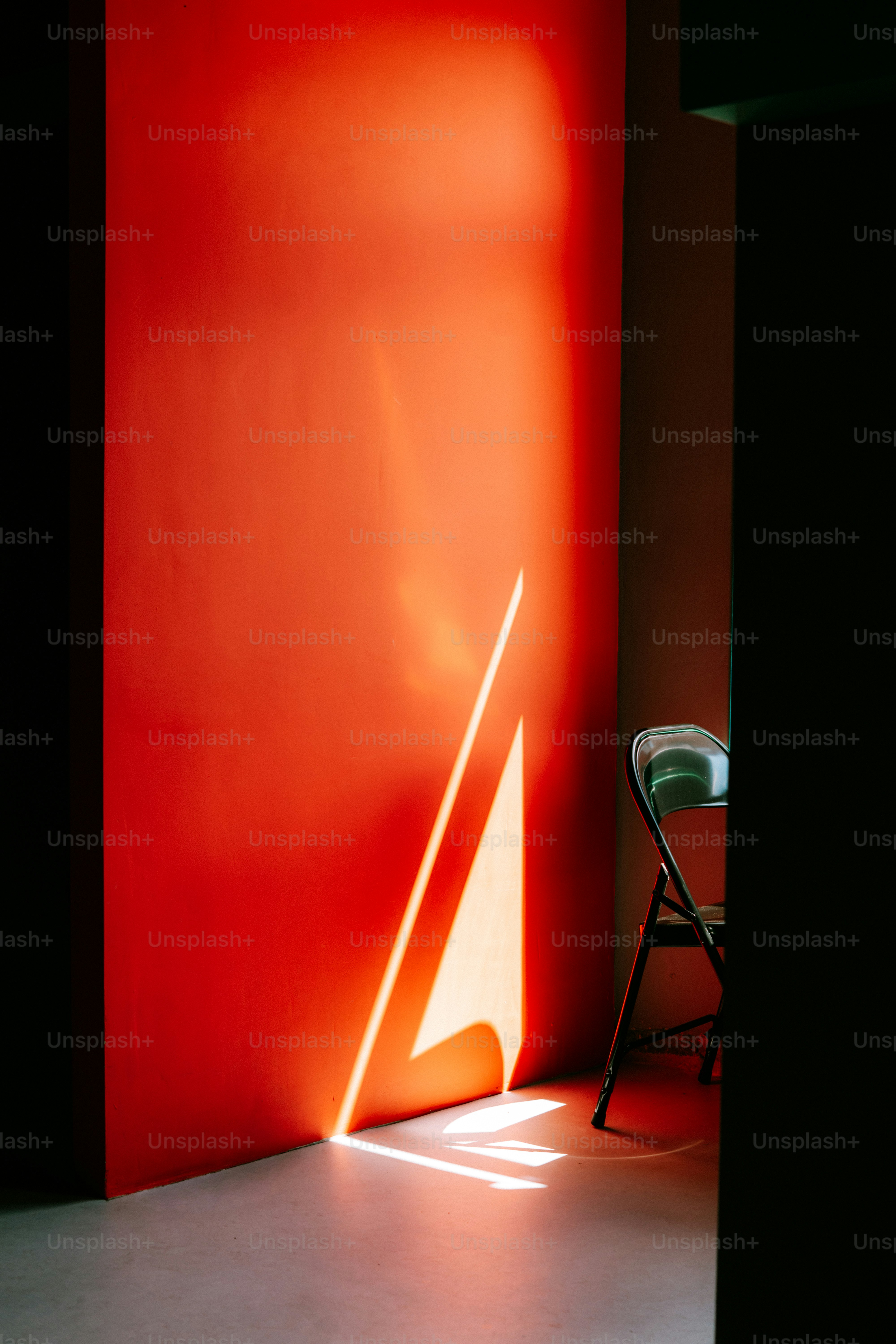 Diagonal sunlight on red wall with folding chair