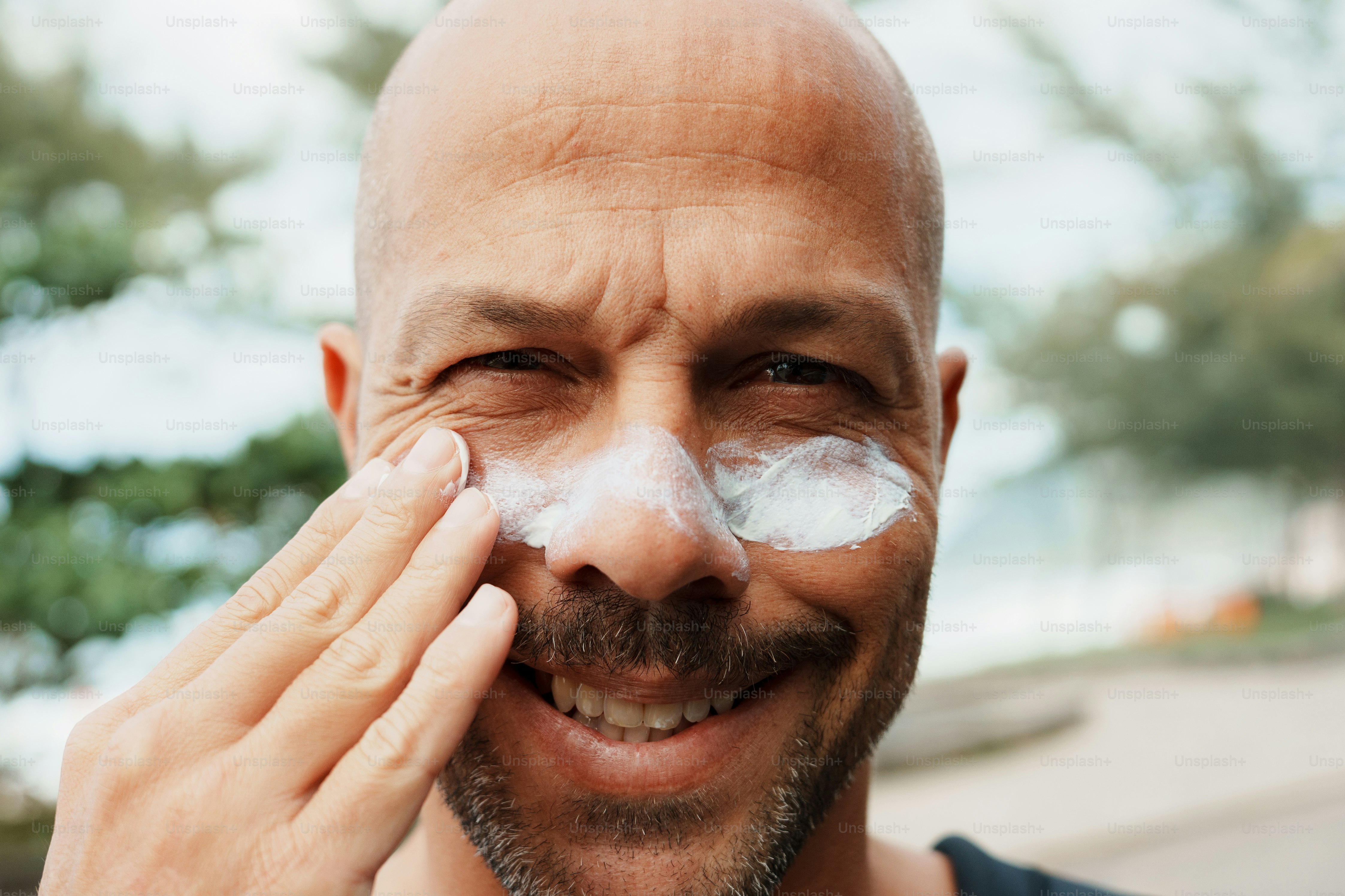 Bald man applying sunscreen to his face