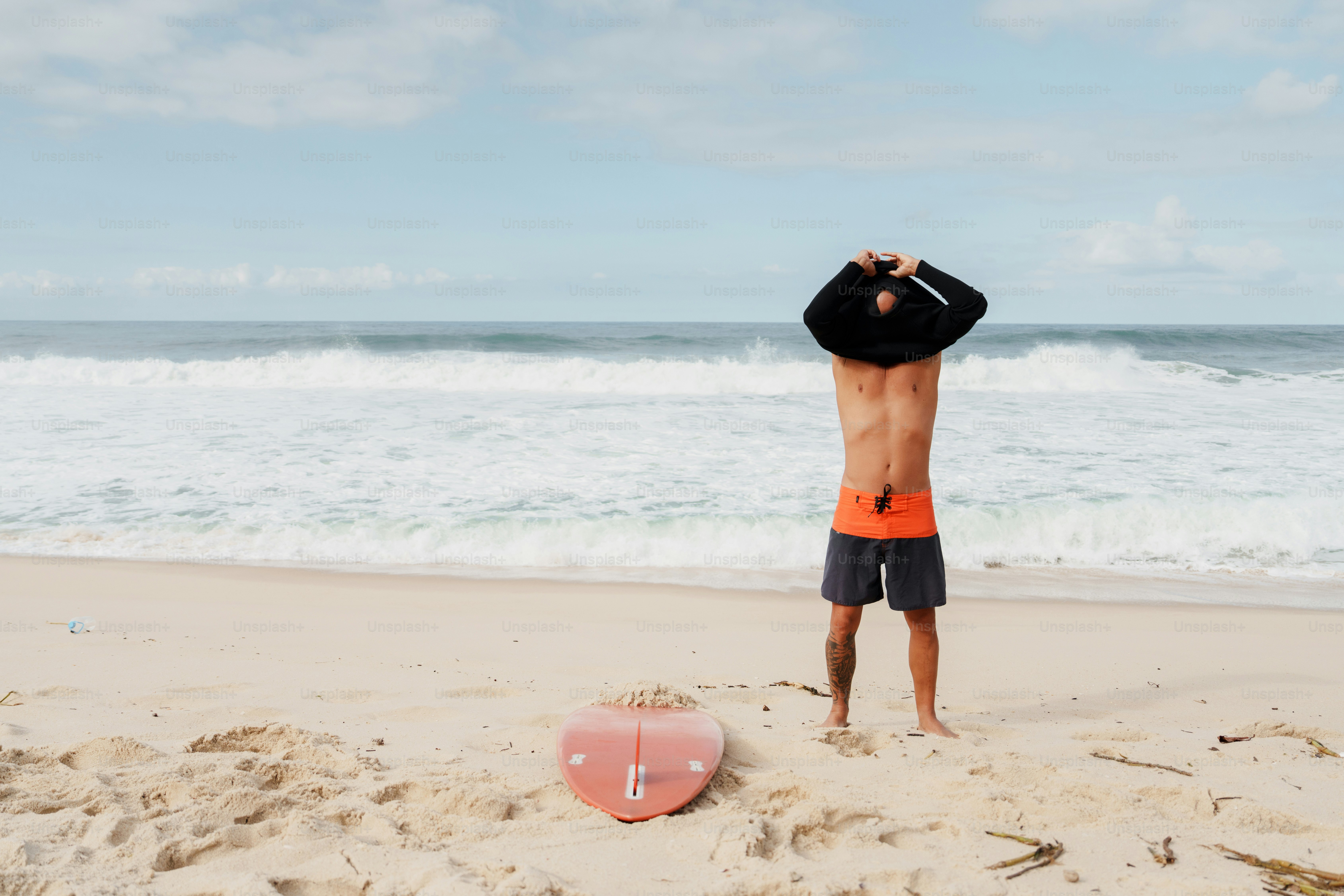 Surfer changing shirt on sandy beach