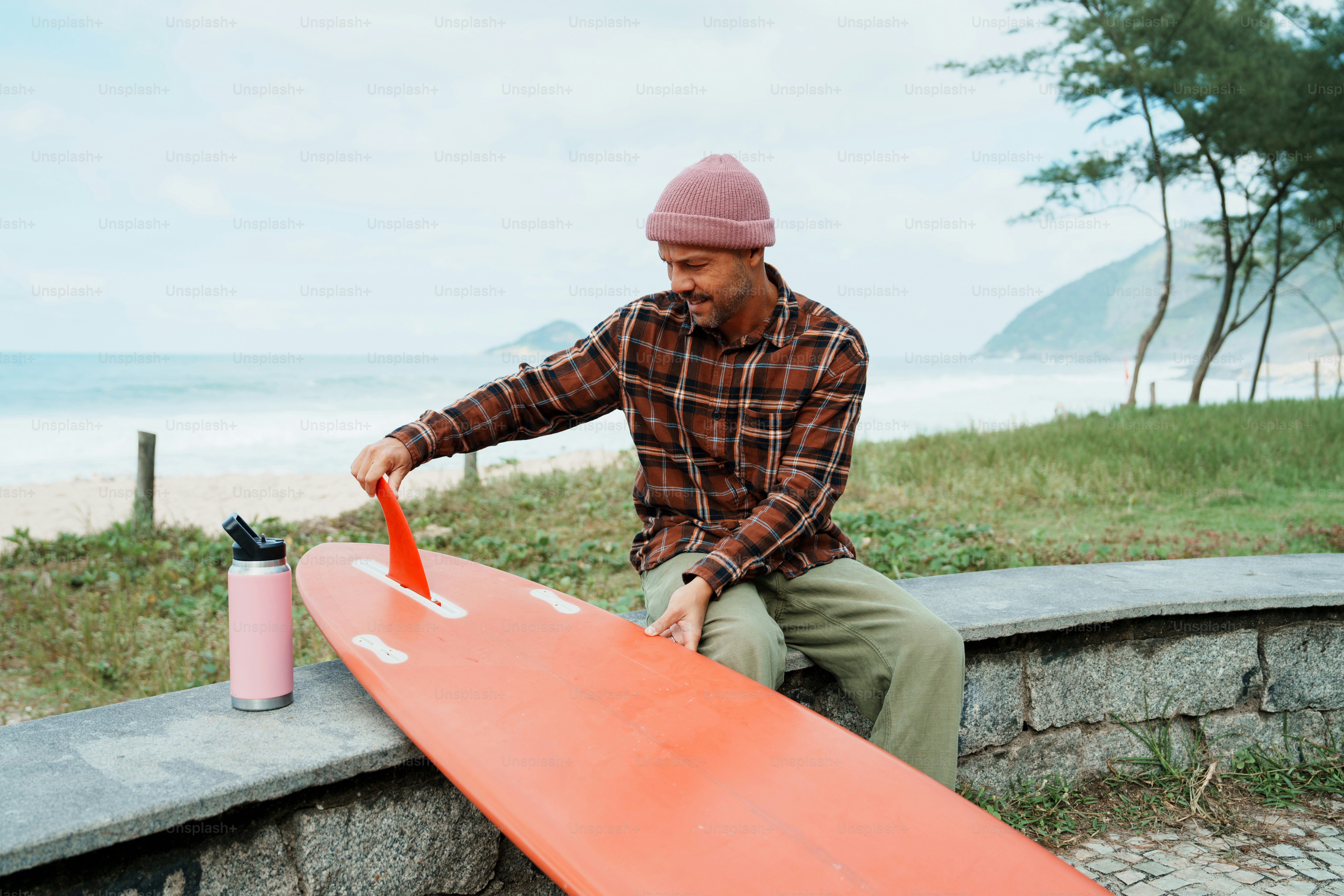 Surfer attaching fin to surfboard on beach