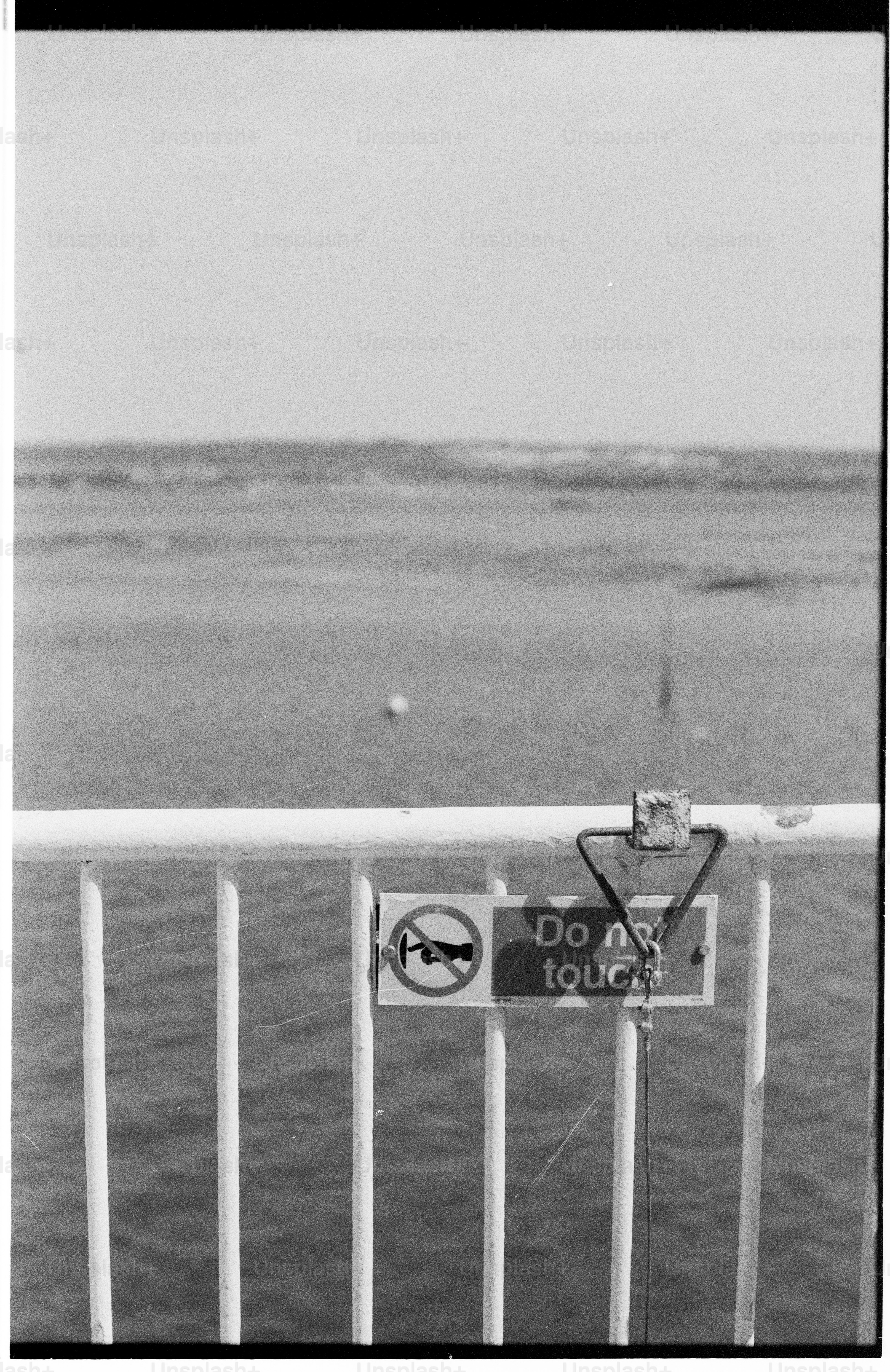 Water behind railing with 'do not touch' sign