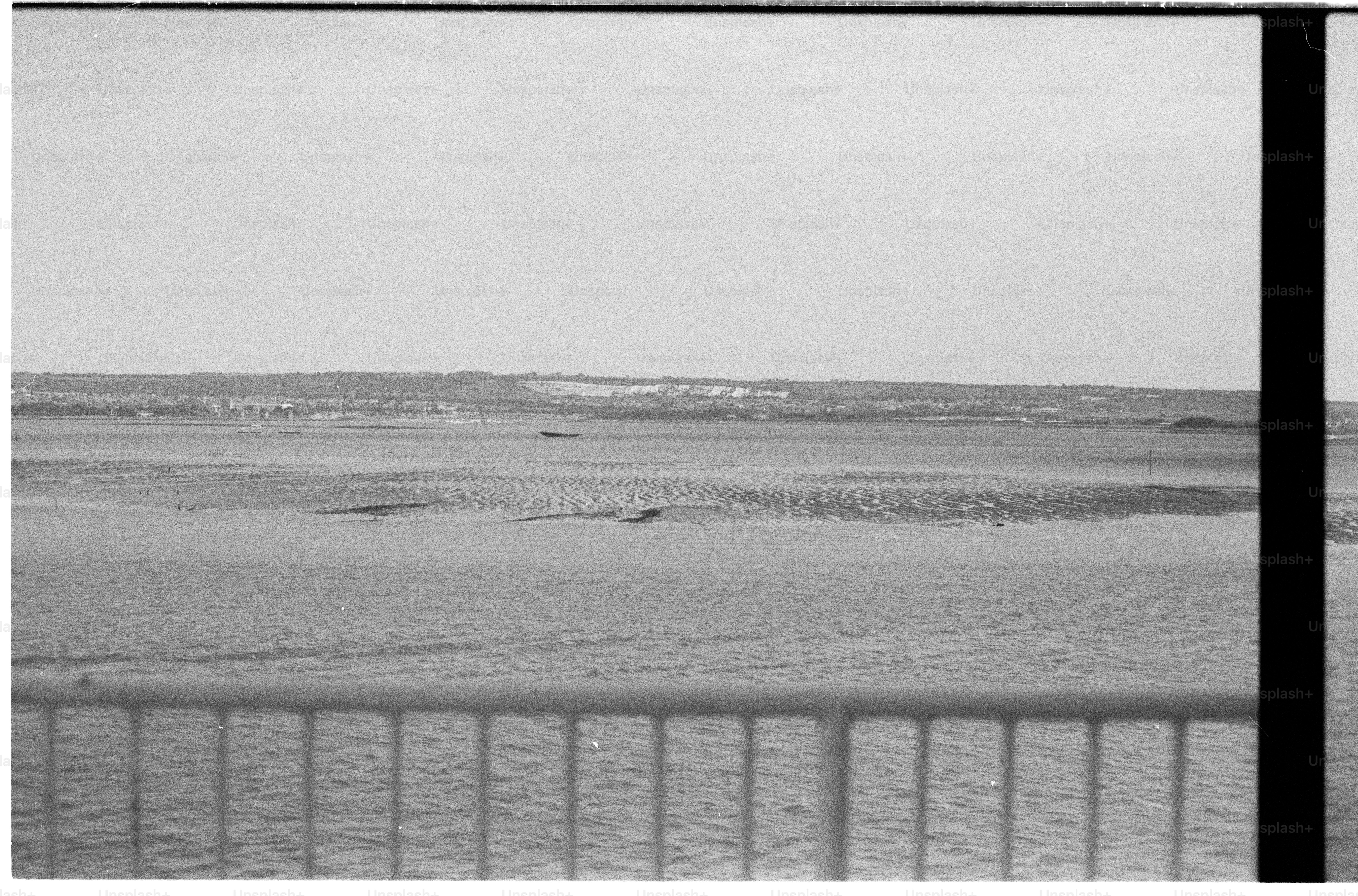 Black and white sandy beach, ocean, and railing