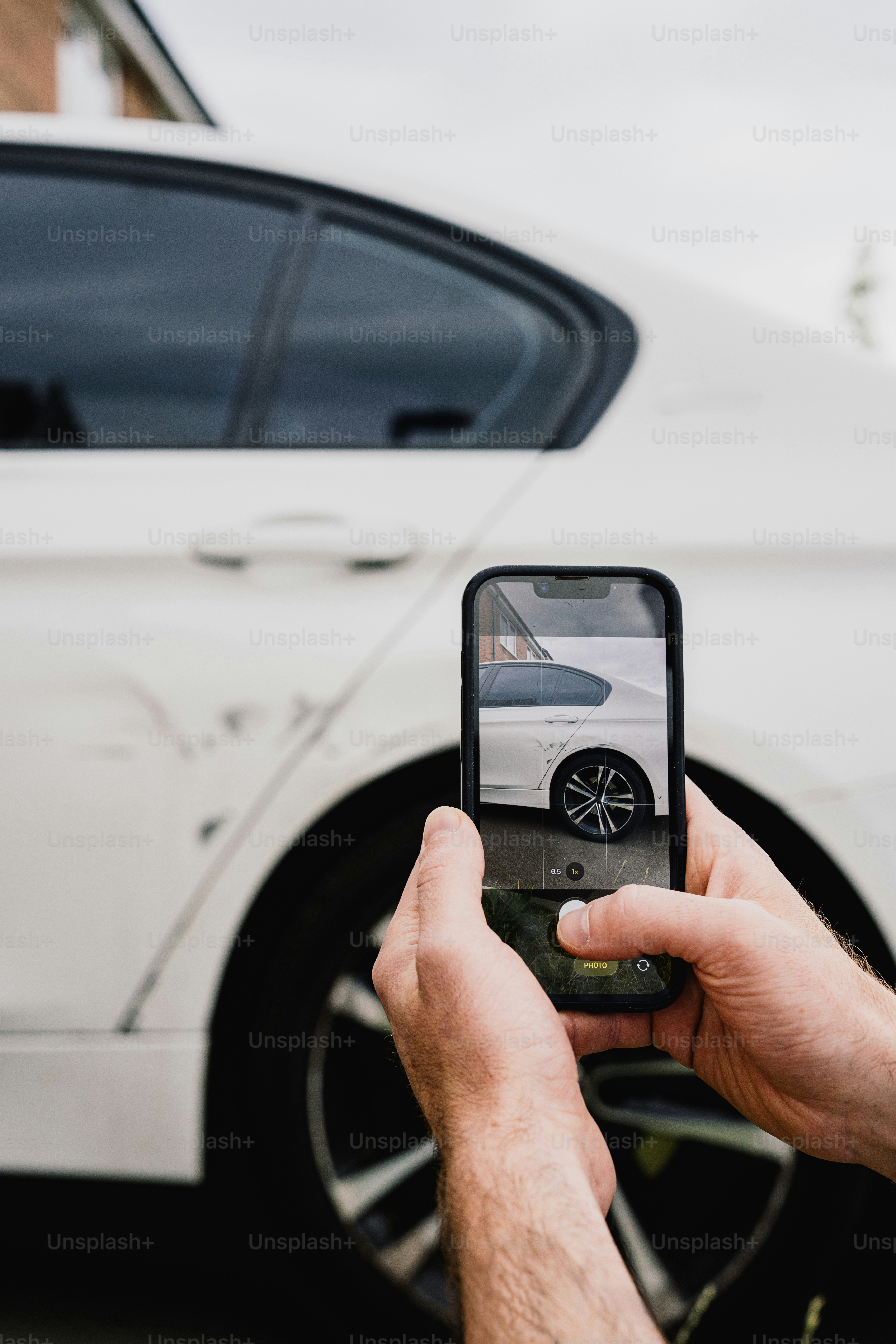 Smartphone photographing damaged white car