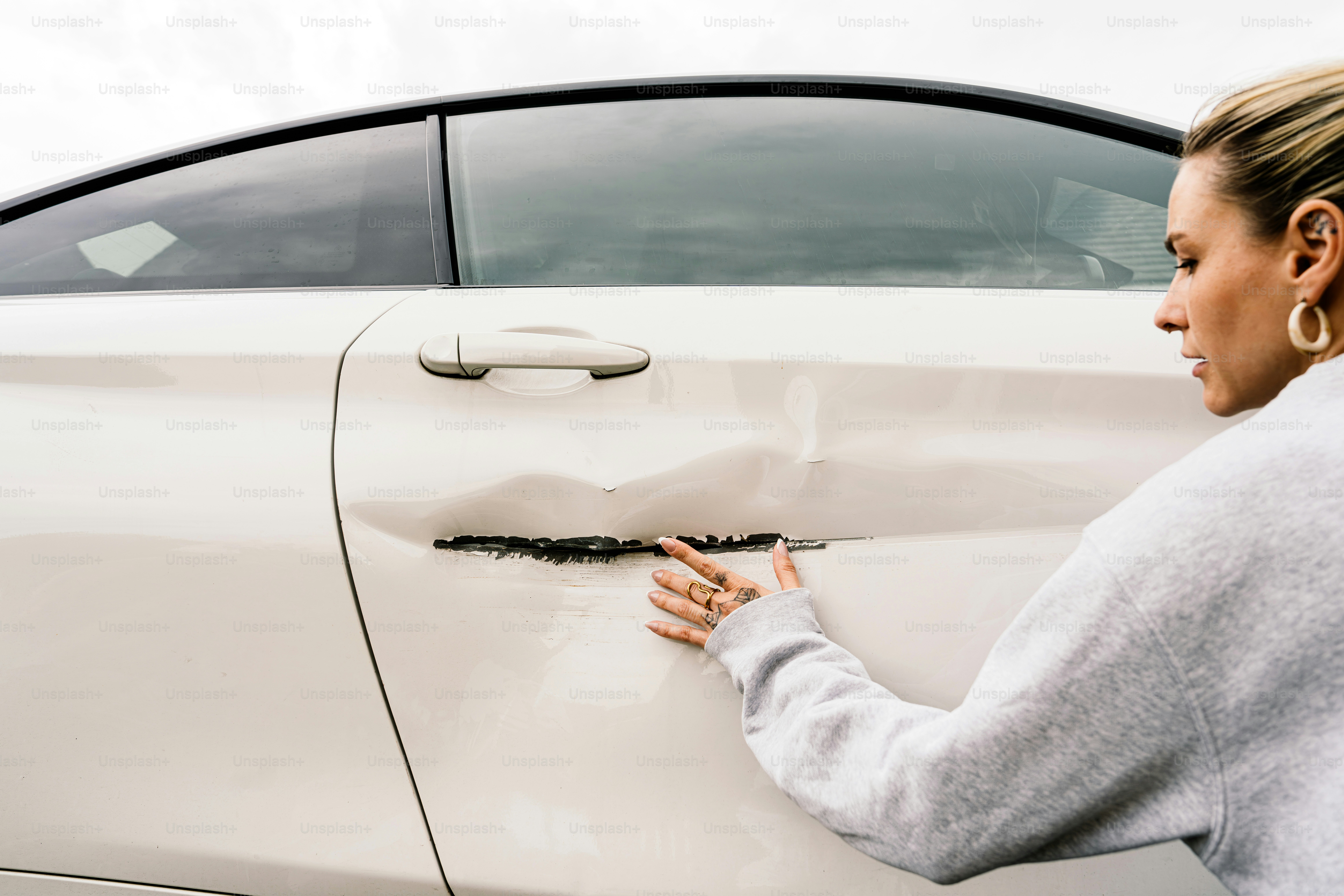 Woman inspecting a damaged white car door