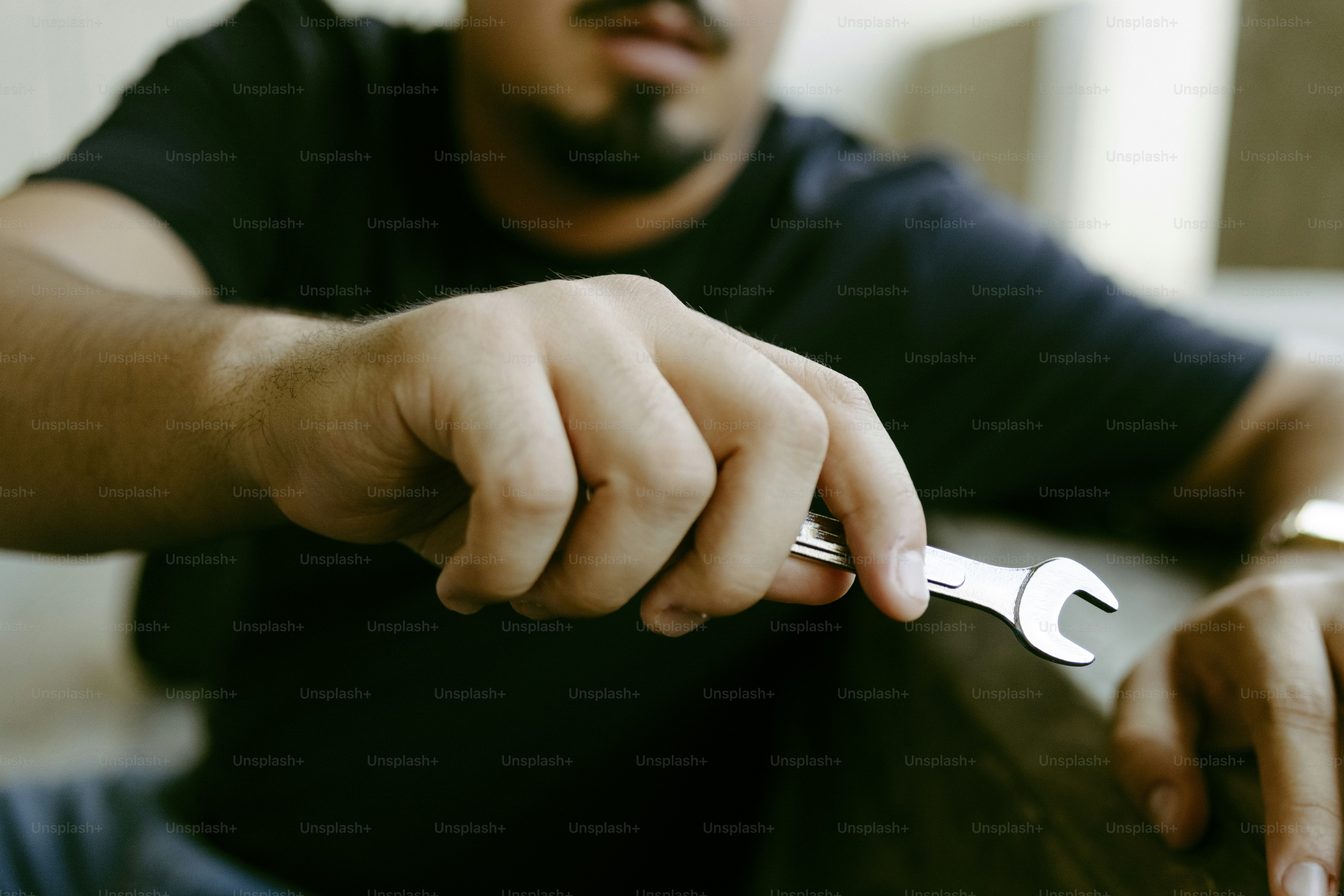 Man holding a small silver wrench