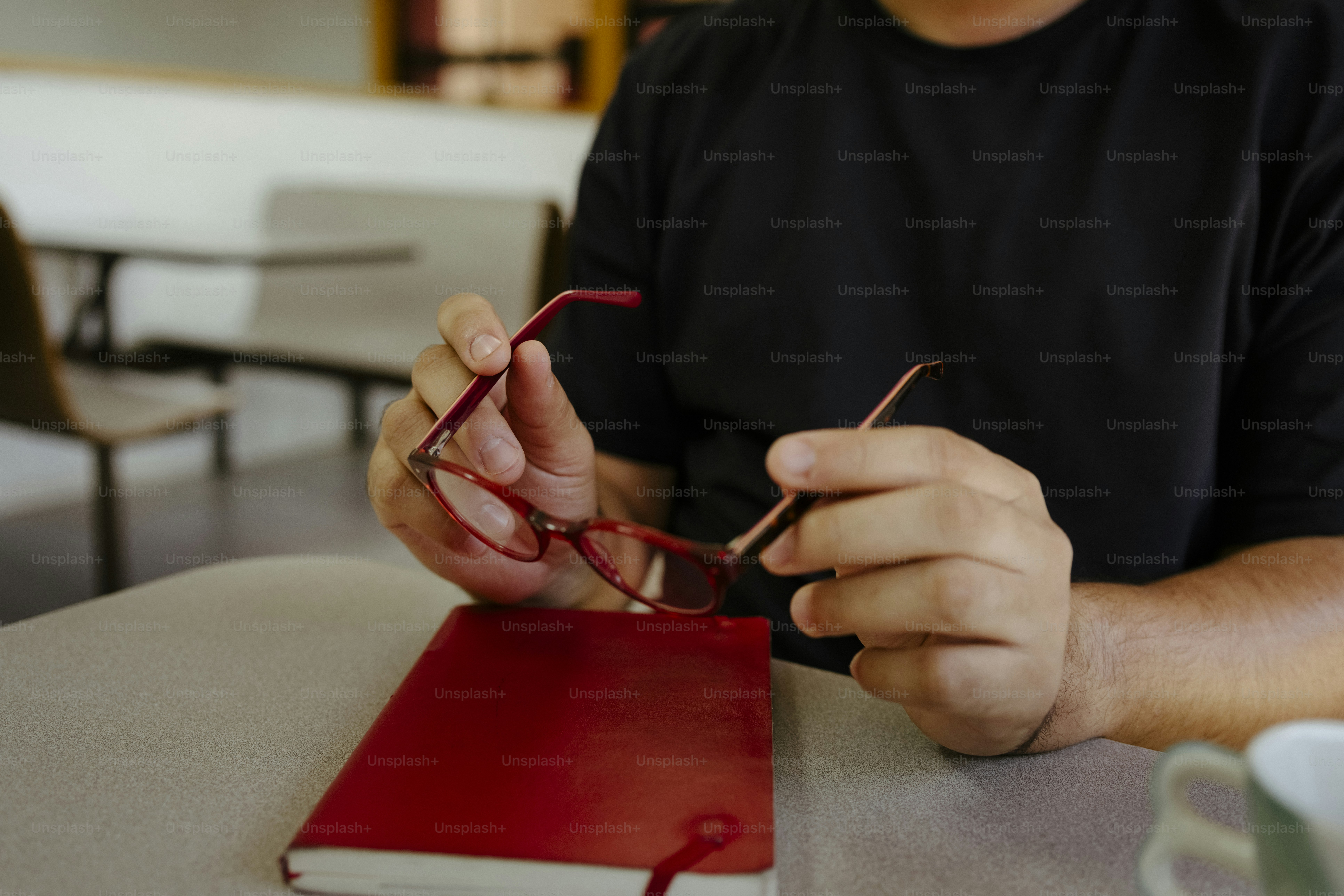 Hands holding red glasses above a red notebook