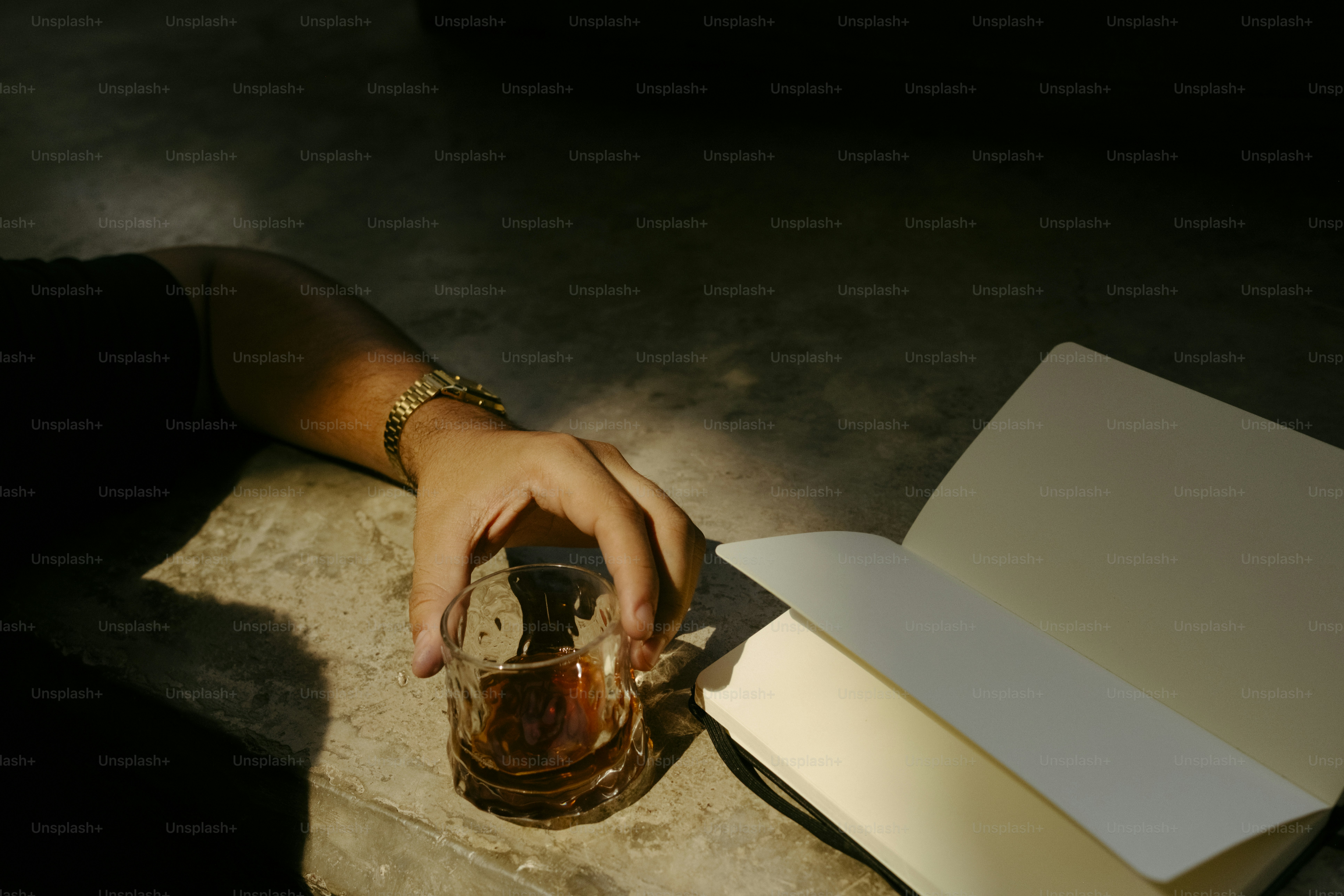 Hand holding drink, open book in dramatic light