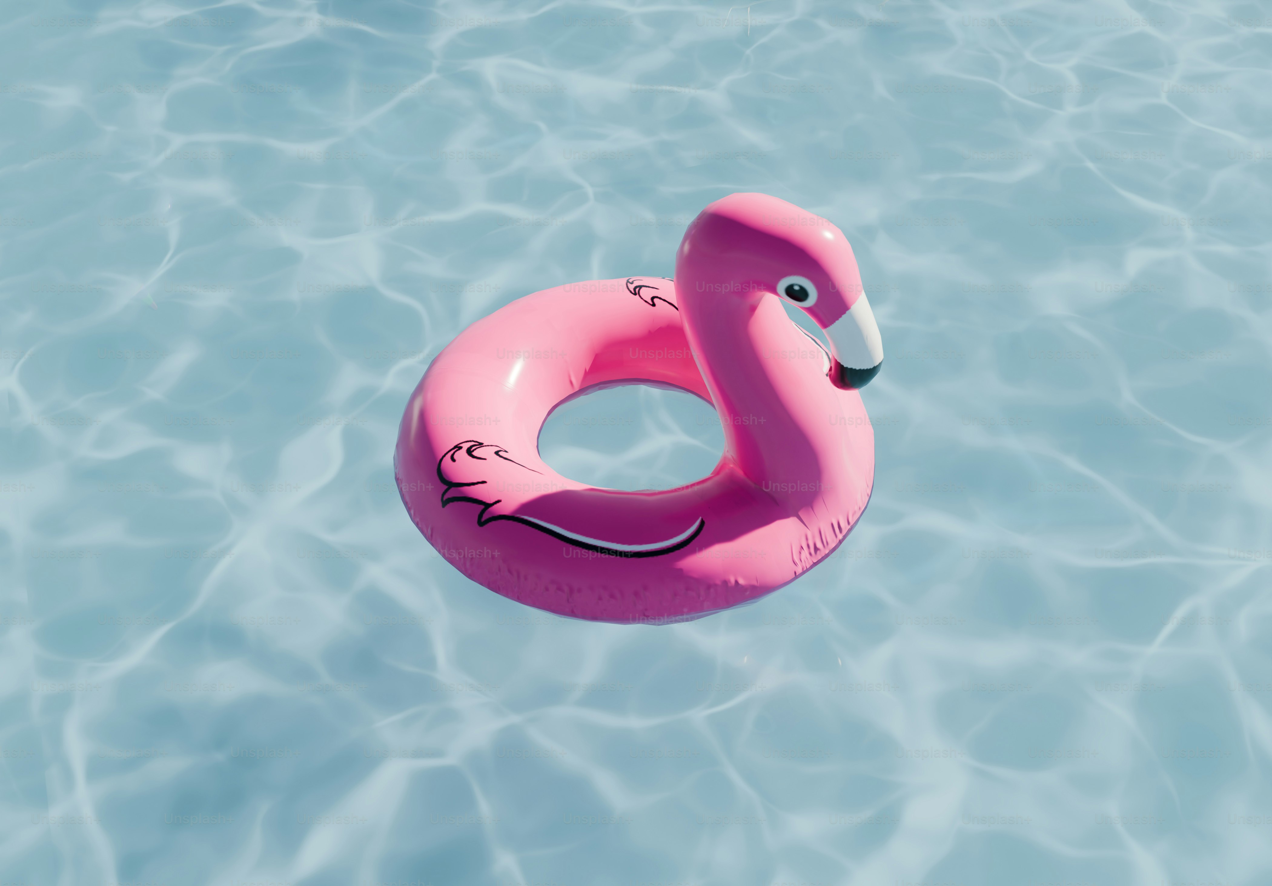 Anneau gonflable de flamant rose flottant dans l’eau bleue