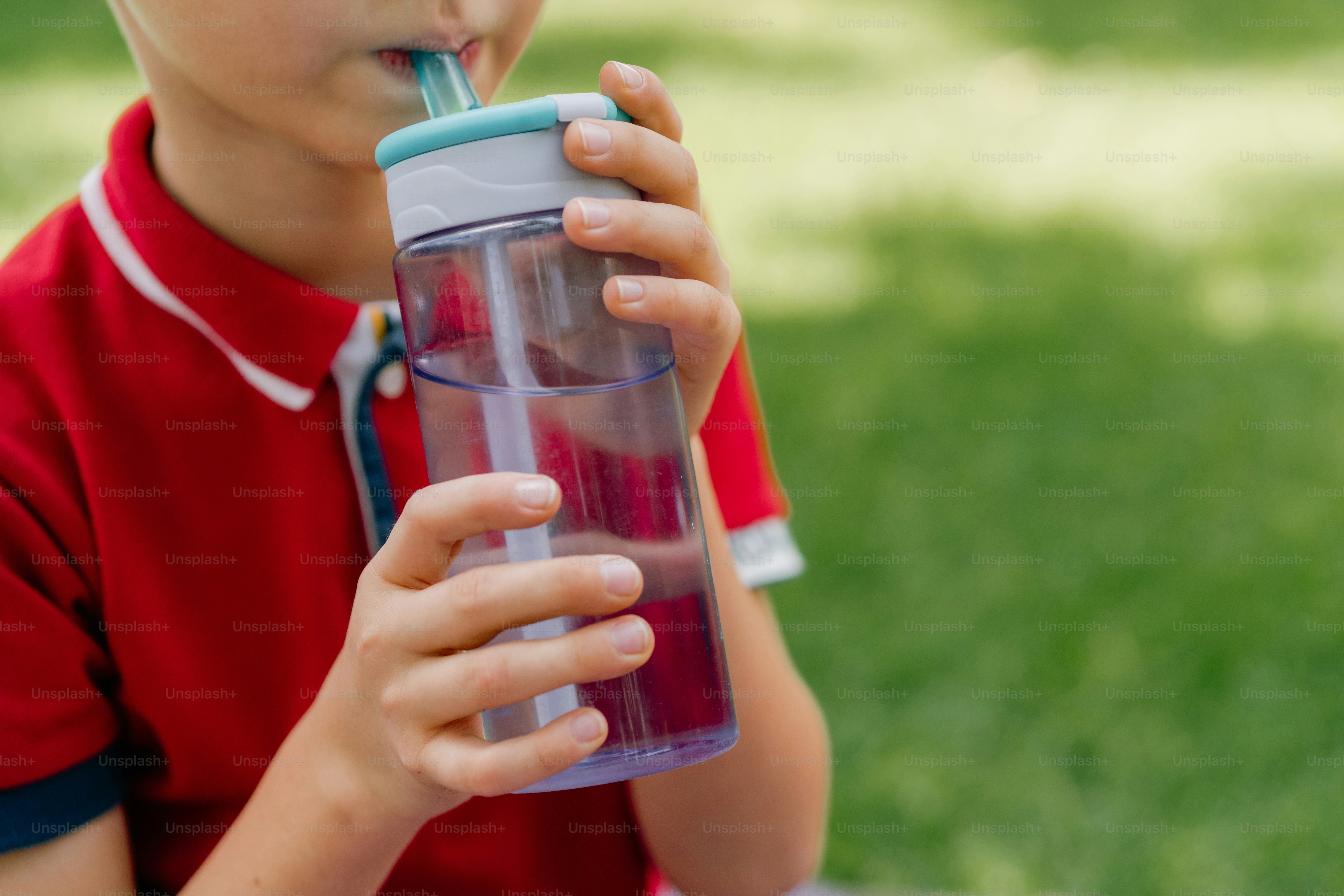 Kleines Kind, das draußen aus einer Wasserflasche trinkt