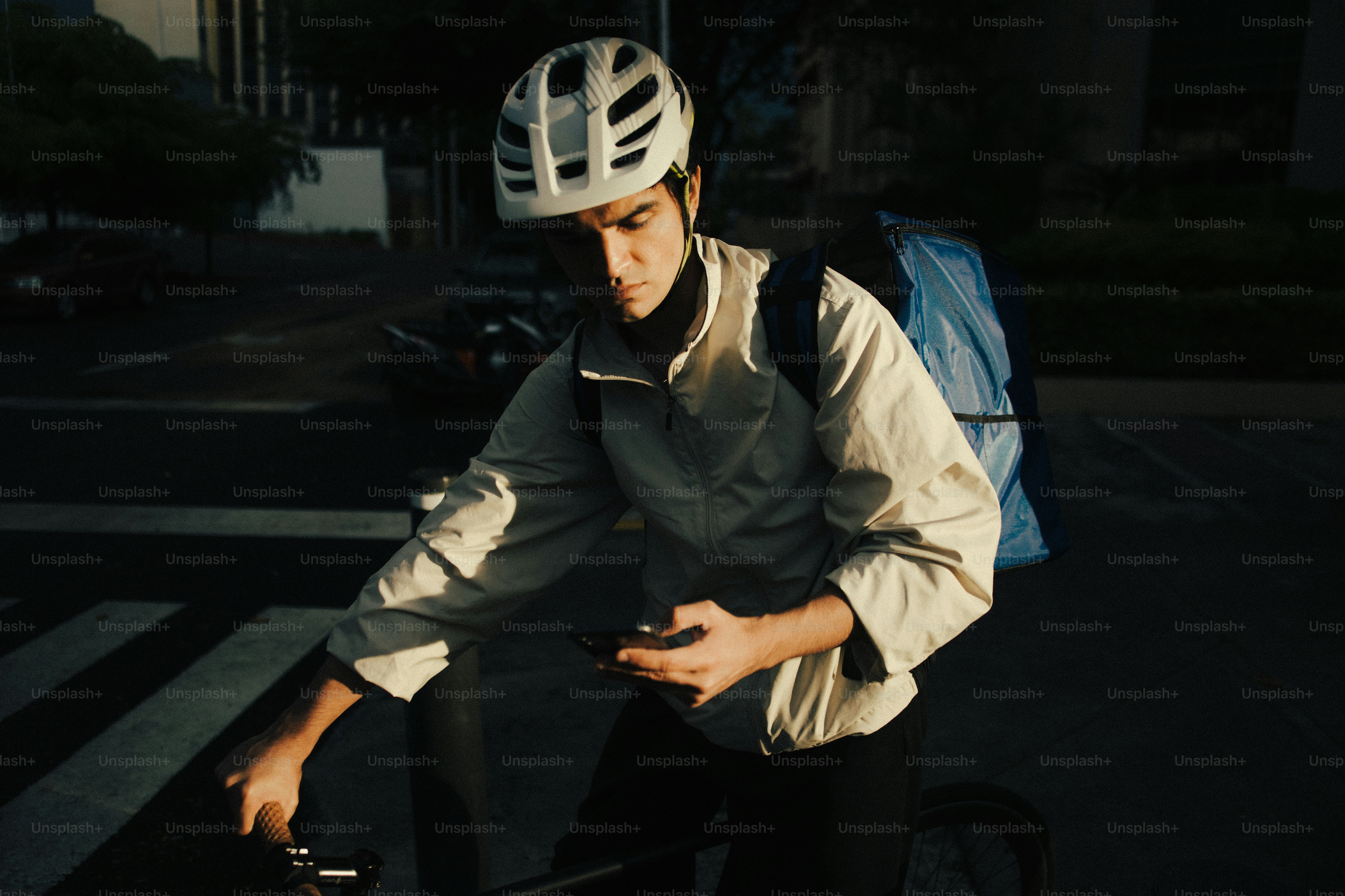 Cyclist wearing helmet and backpack checking phone