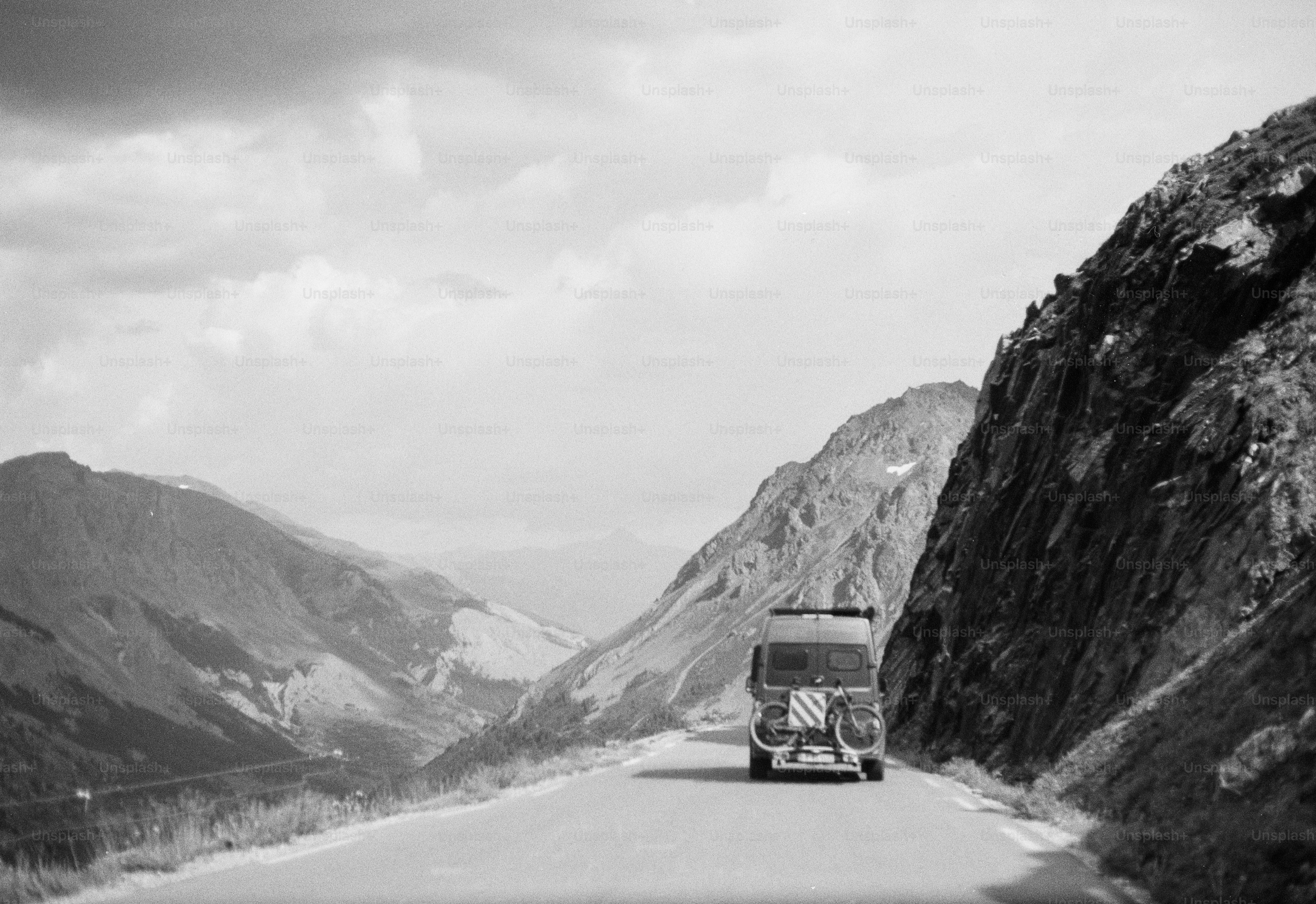 Camper van driving mountain road, black and white