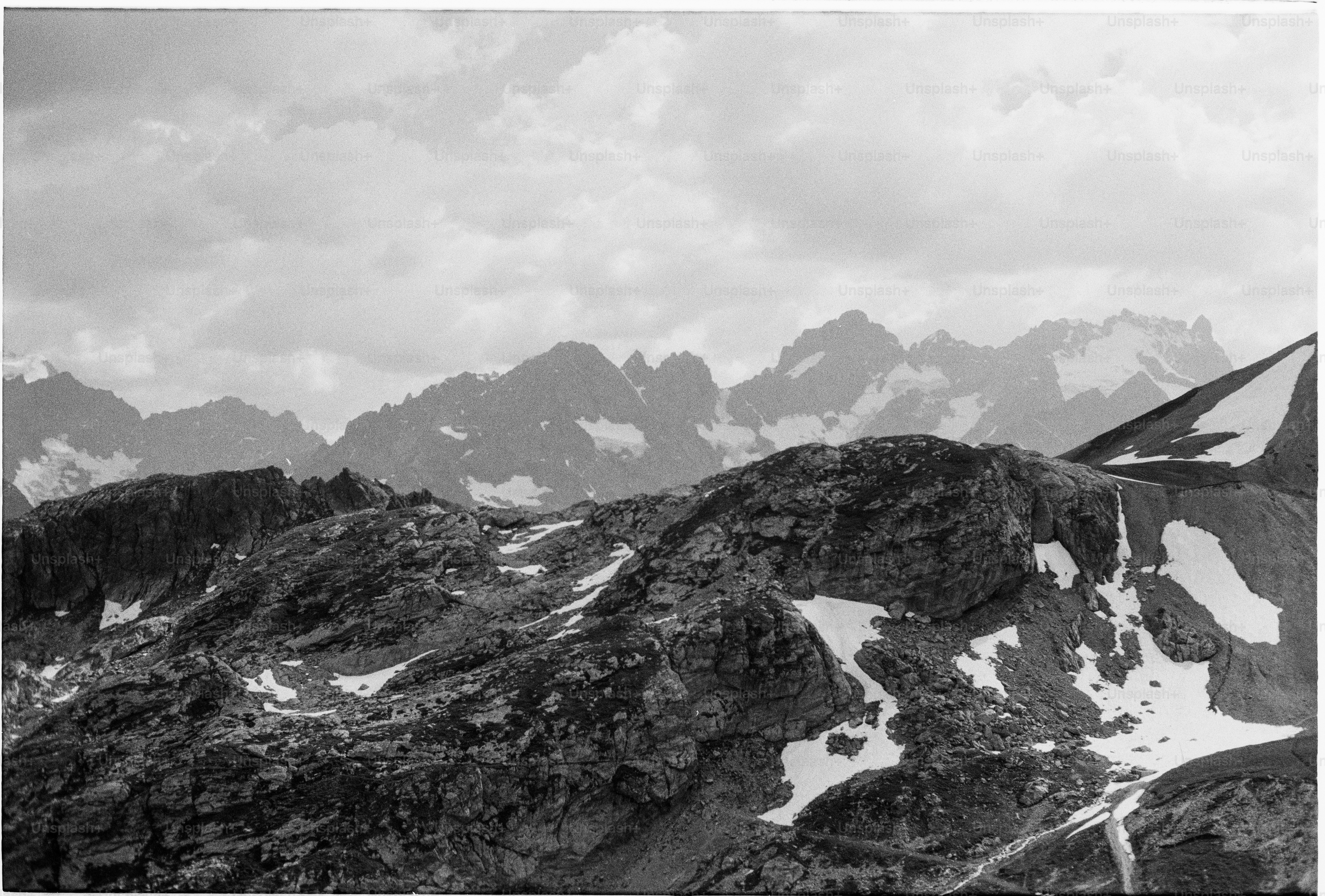 Black and white rocky mountains with snow and cloudy sky