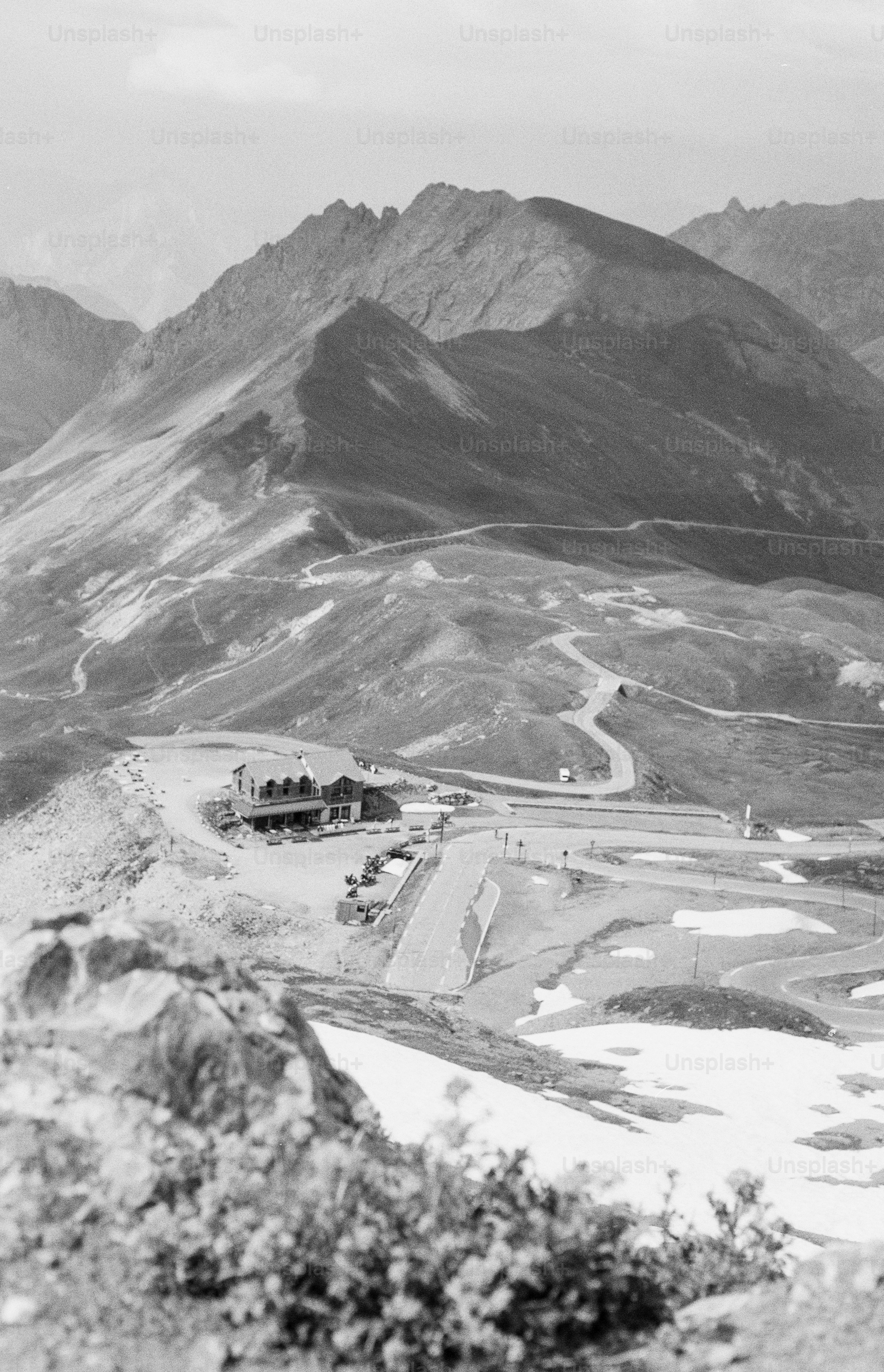 Mountain pass with building, winding roads, and snow.