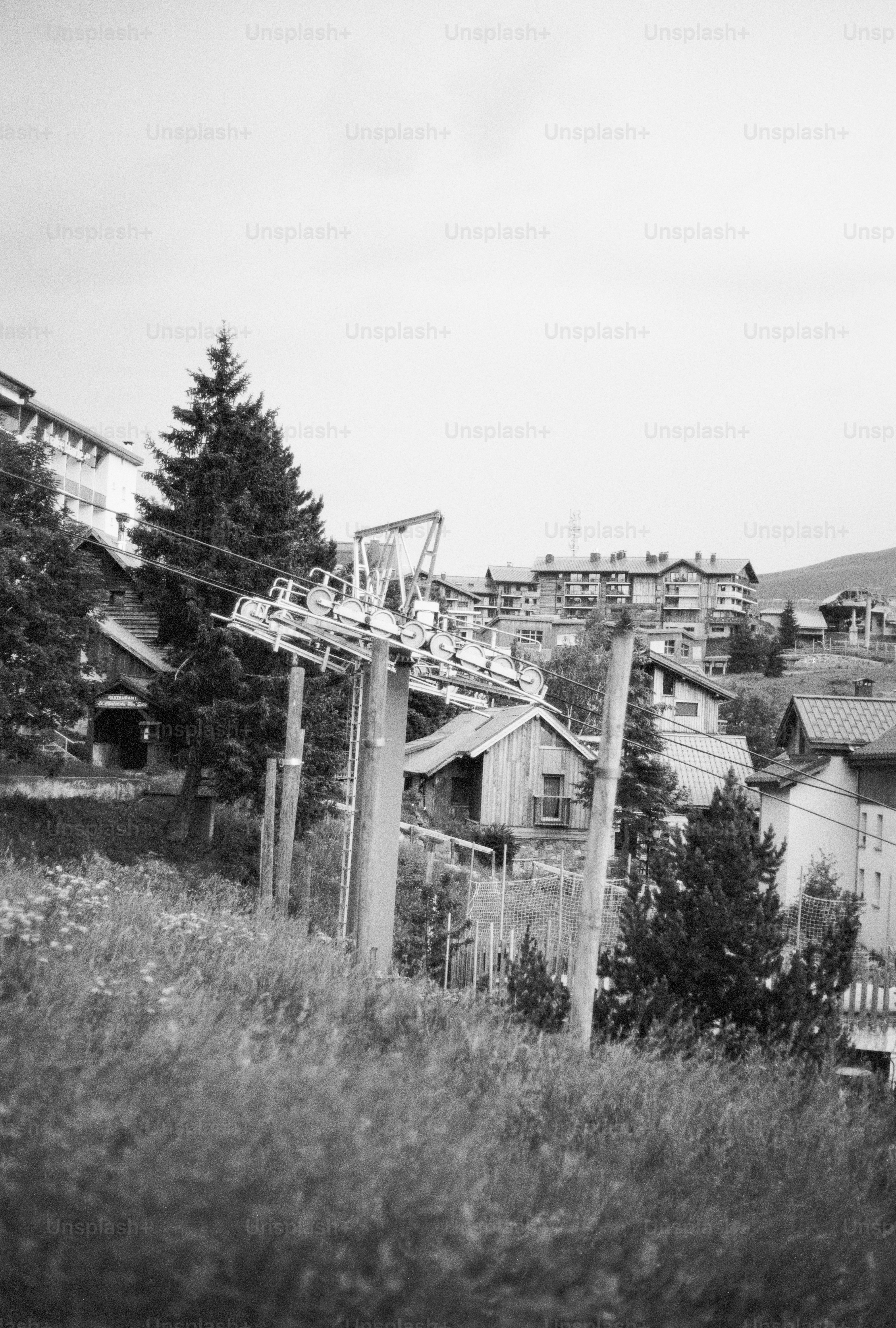 Ski lift on grassy hill with mountain resort buildings
