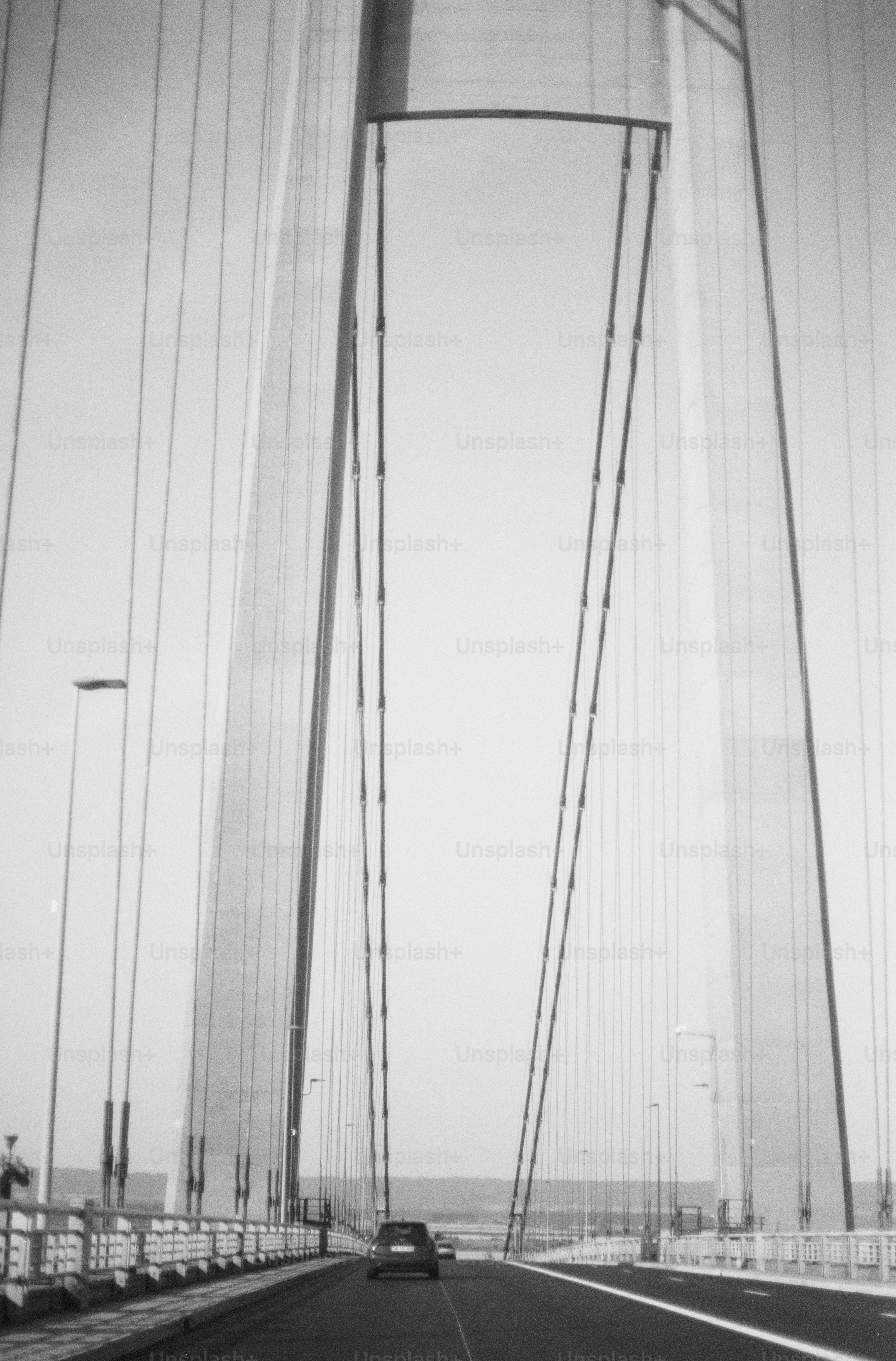 Black and white car driving on suspension bridge