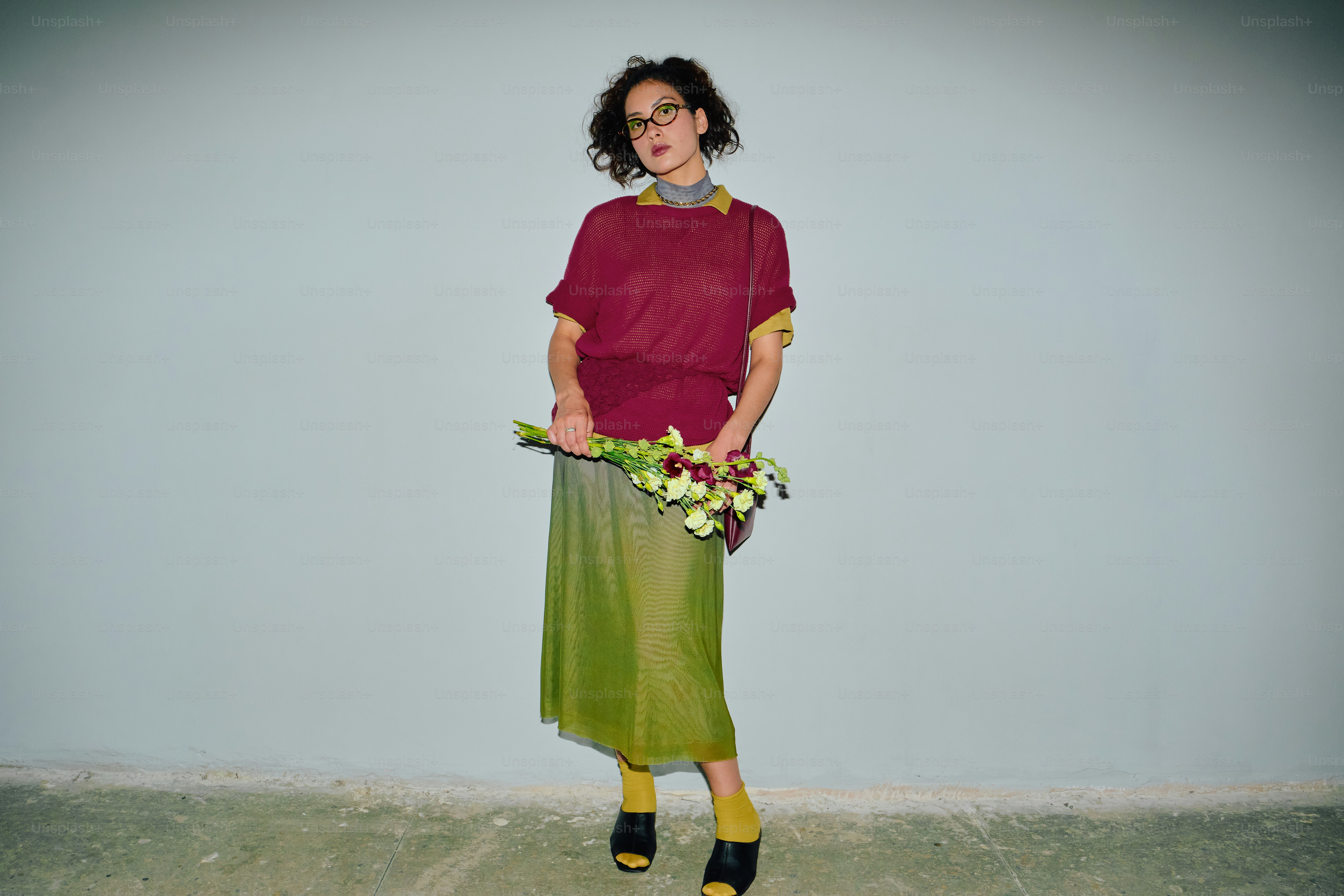 Fashionable woman in burgundy and chartreuse holding flowers