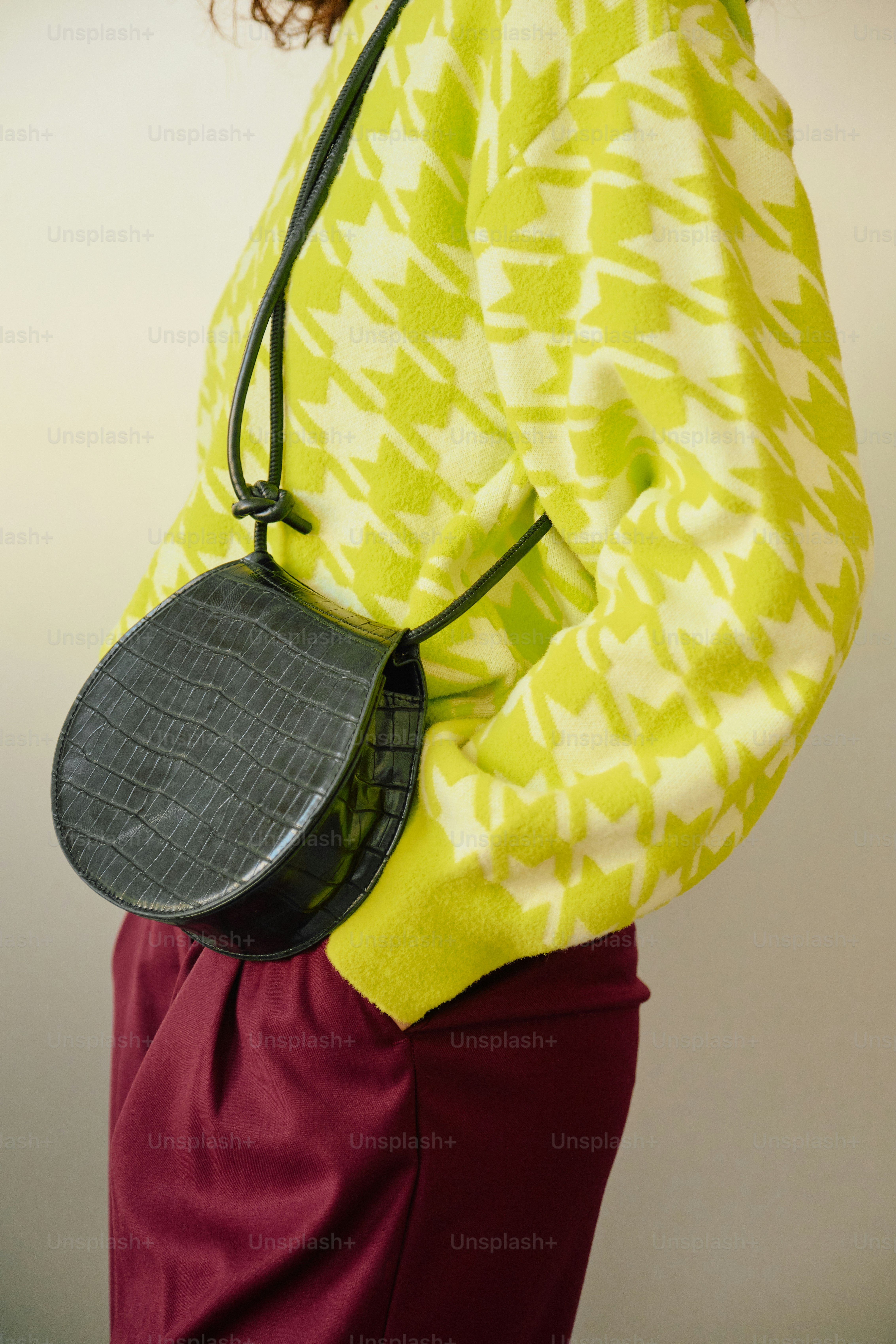 Chartreuse houndstooth sweater, burgundy pants, and crocodile-embossed bag
