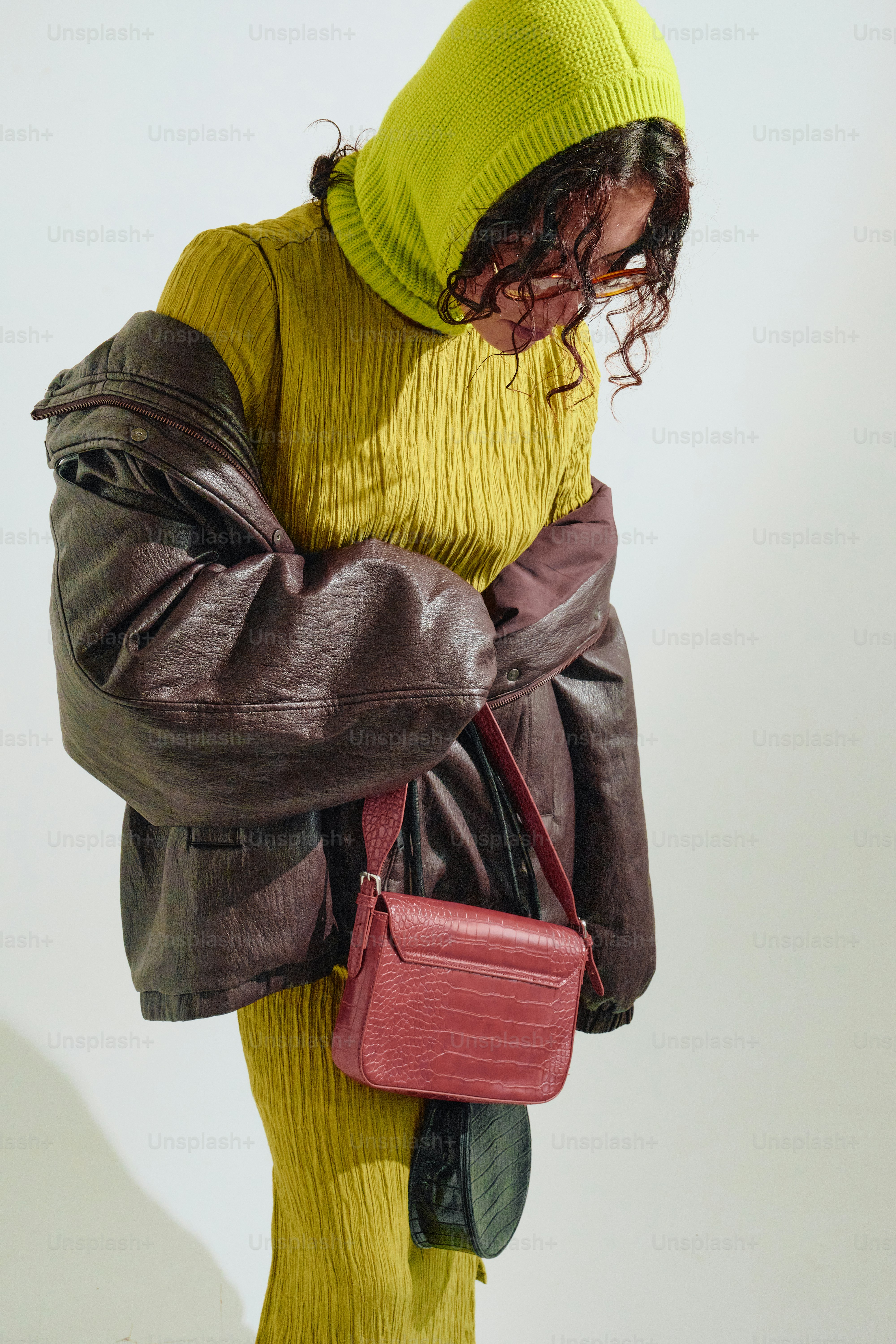 Woman in chartreuse outfit with burgundy jacket and bag