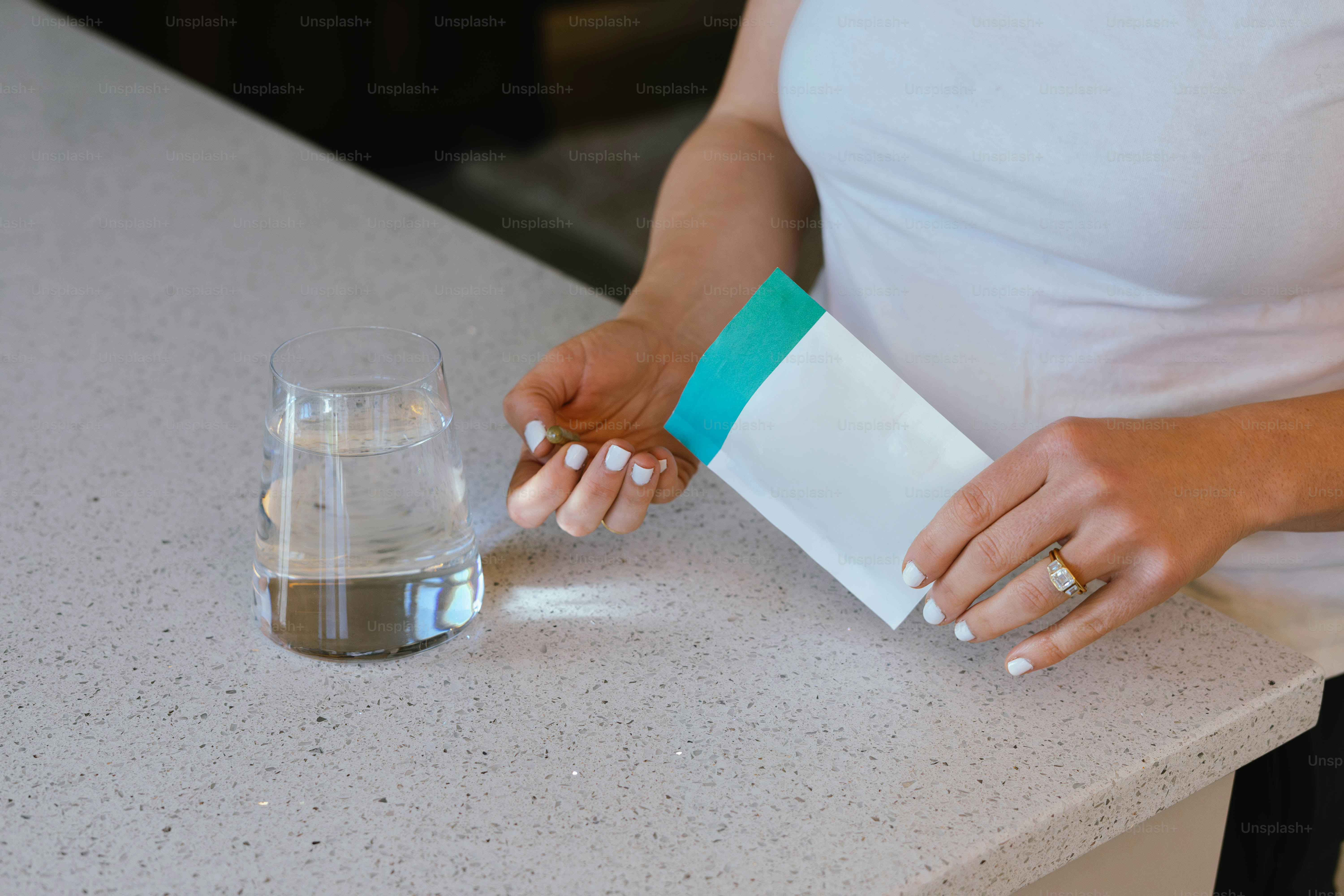Hands holding packet over glass of water