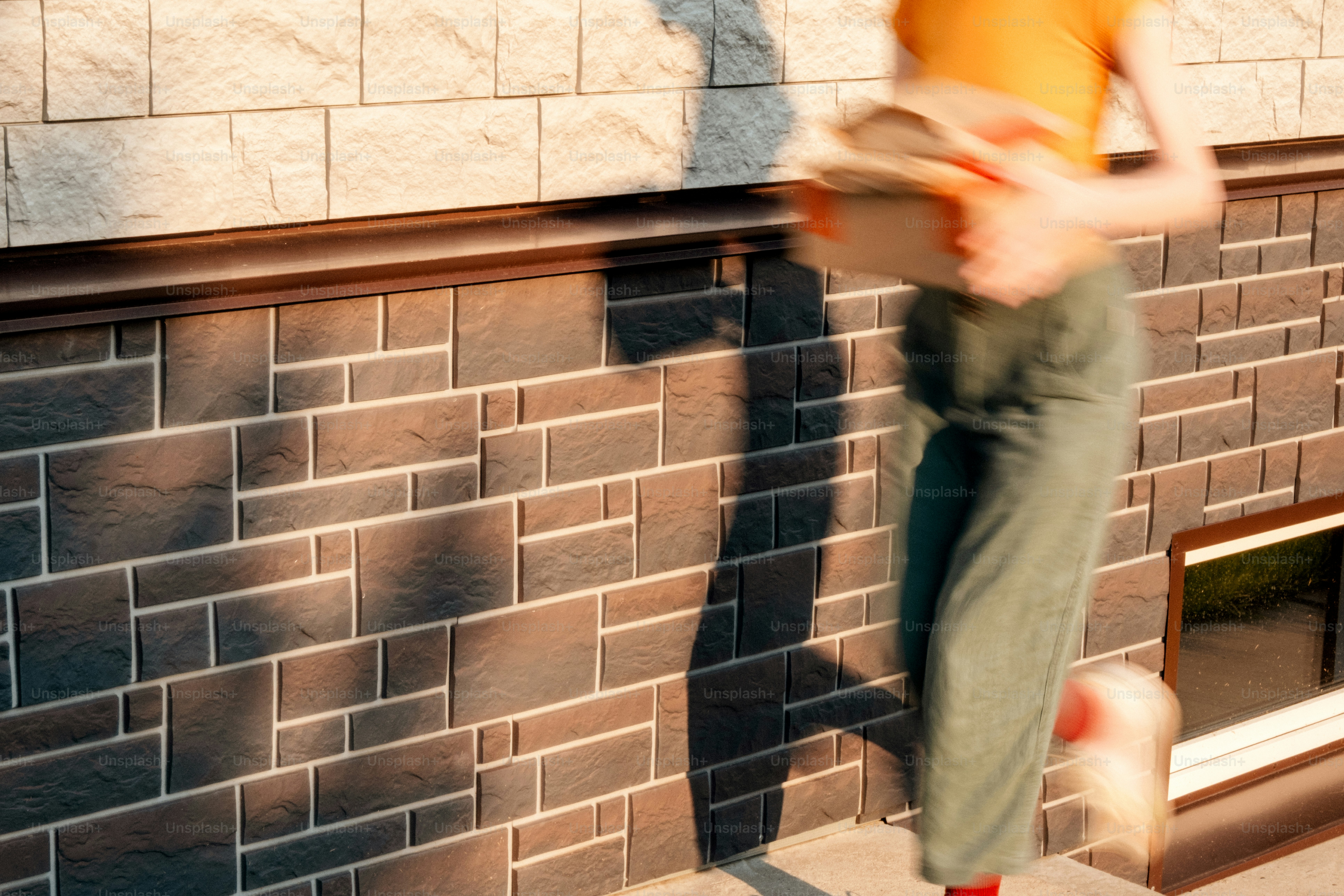 Woman quickly running with a package by brick wall